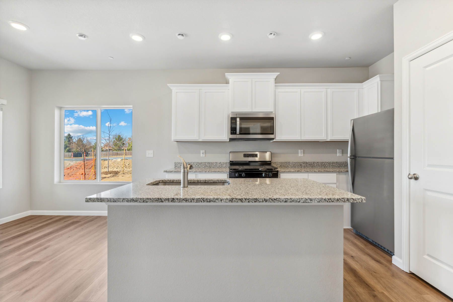 The kitchen has stainless steel appliances and plank flooring.