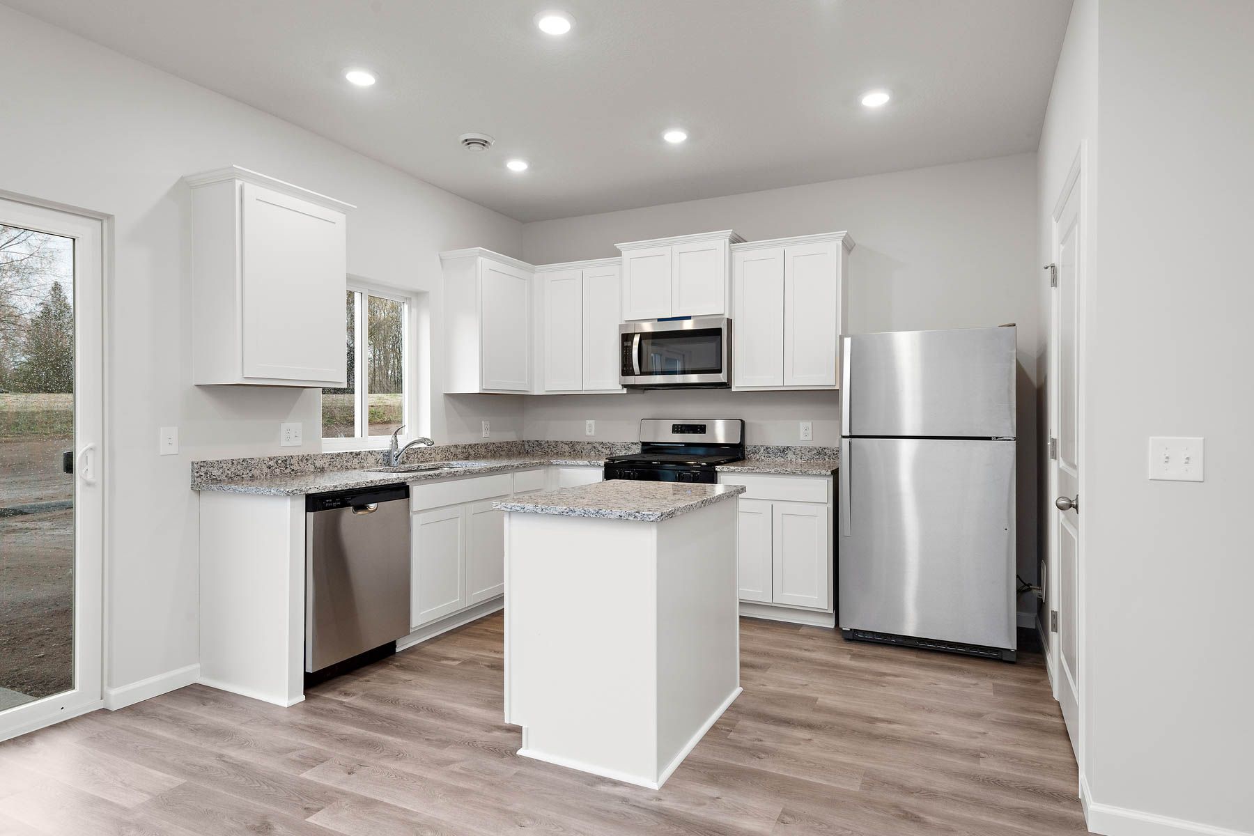 The kitchen has stainless steel appliances and plank flooring.