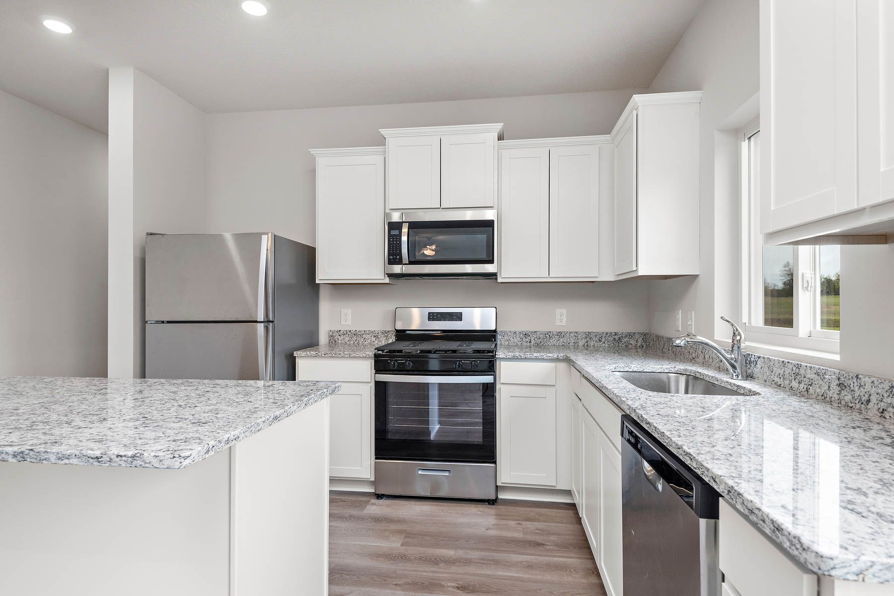 The kitchen has stainless steel appliances and plank flooring.