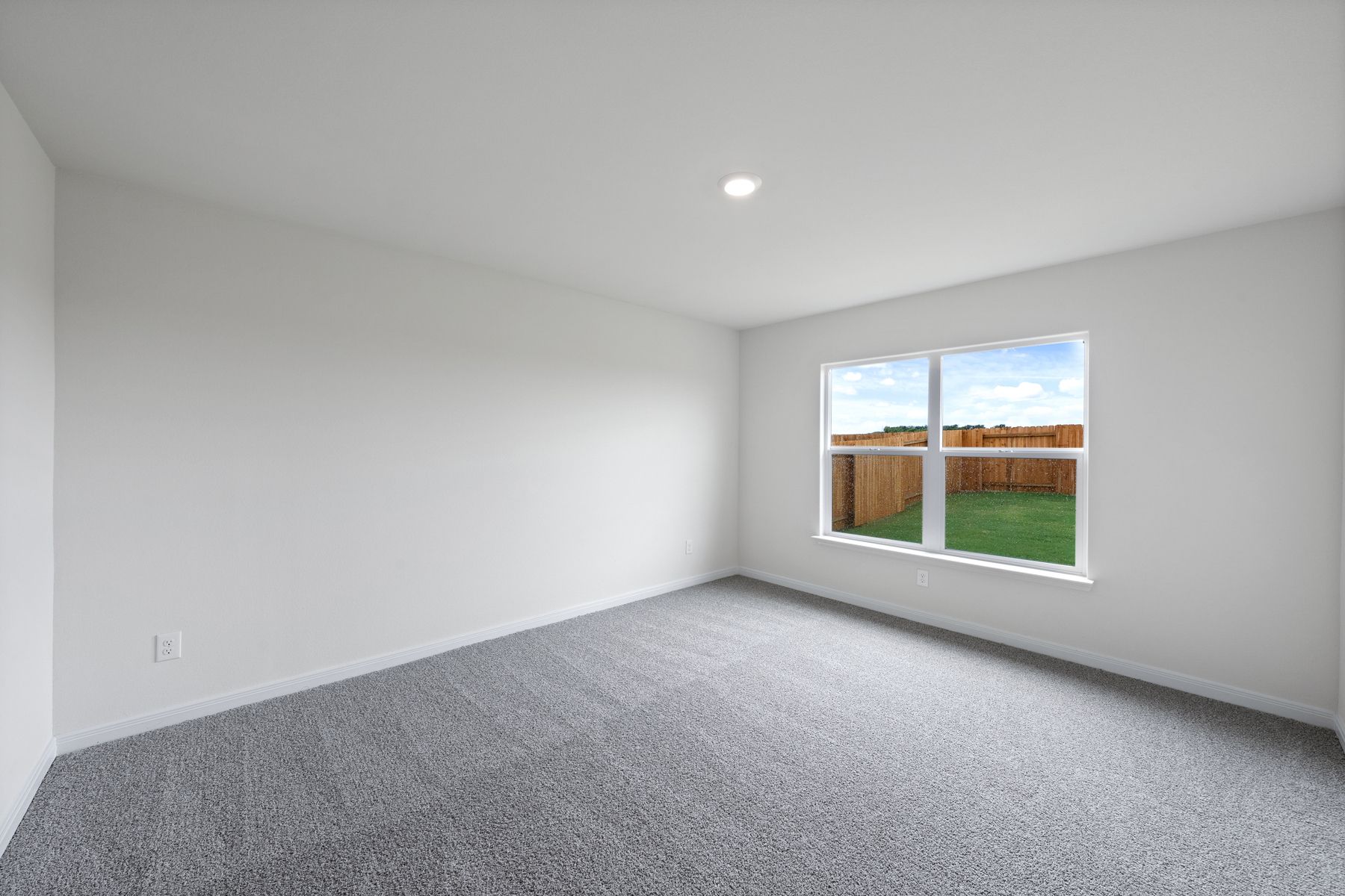 The spacious master bedroom has a large window that lets in natural light and backyard views.