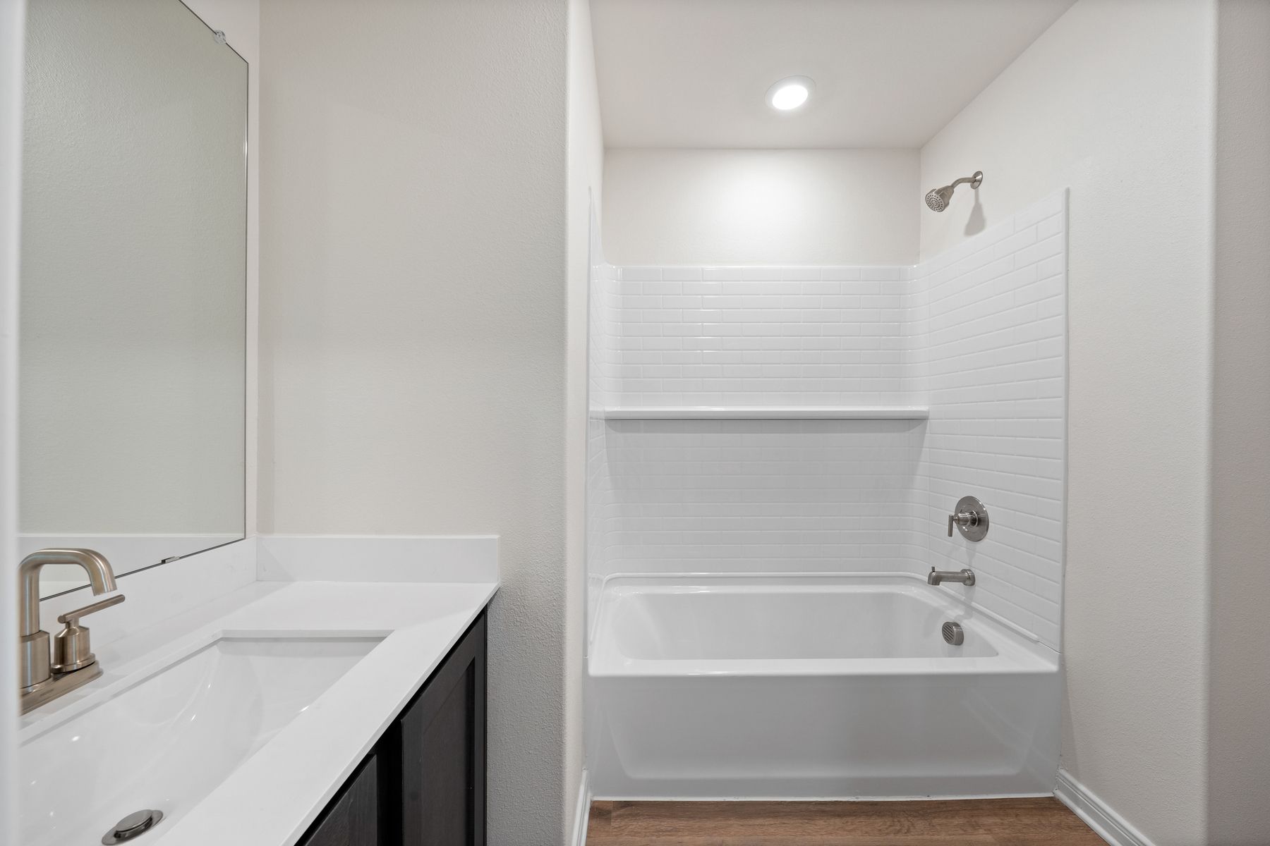 The secondary bathroom has a large vanity space and a shower-tub combo.