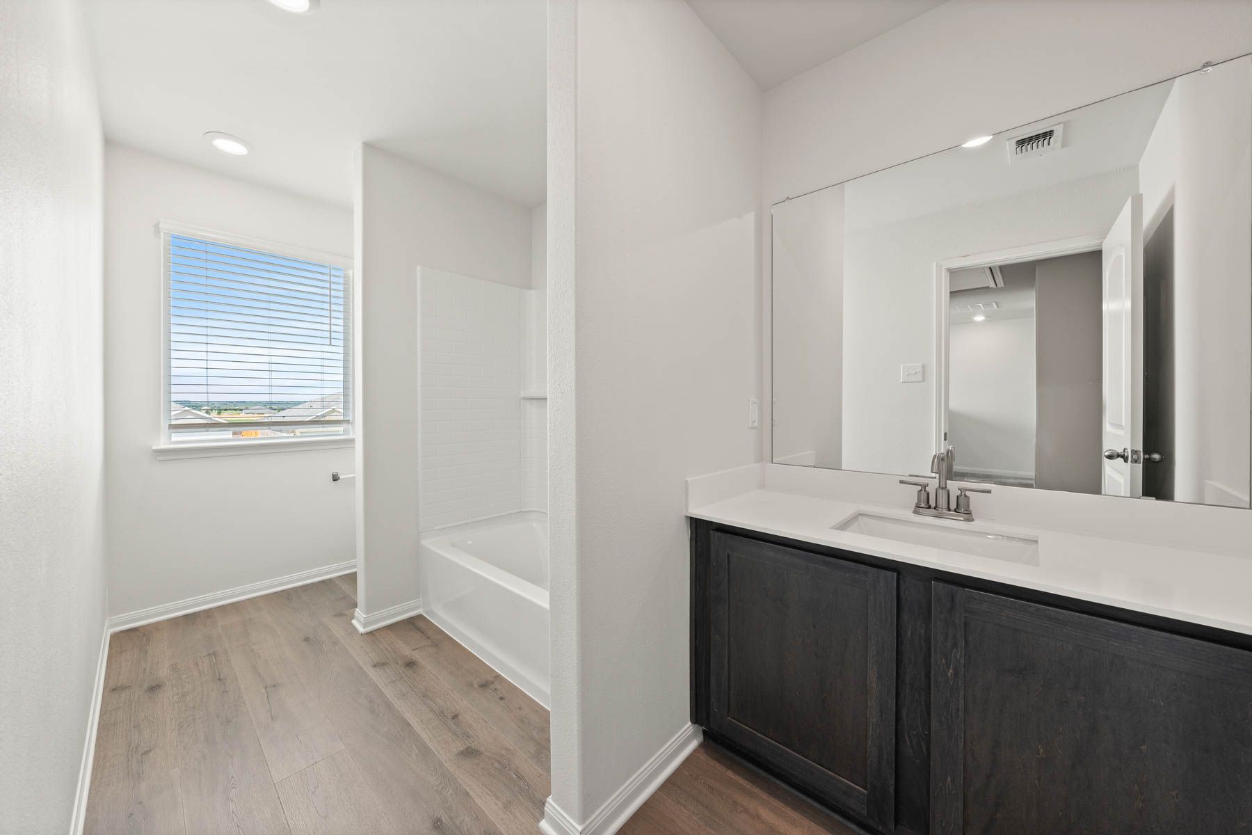 The secondary bathroom has a large vanity space and shower tub combo.
