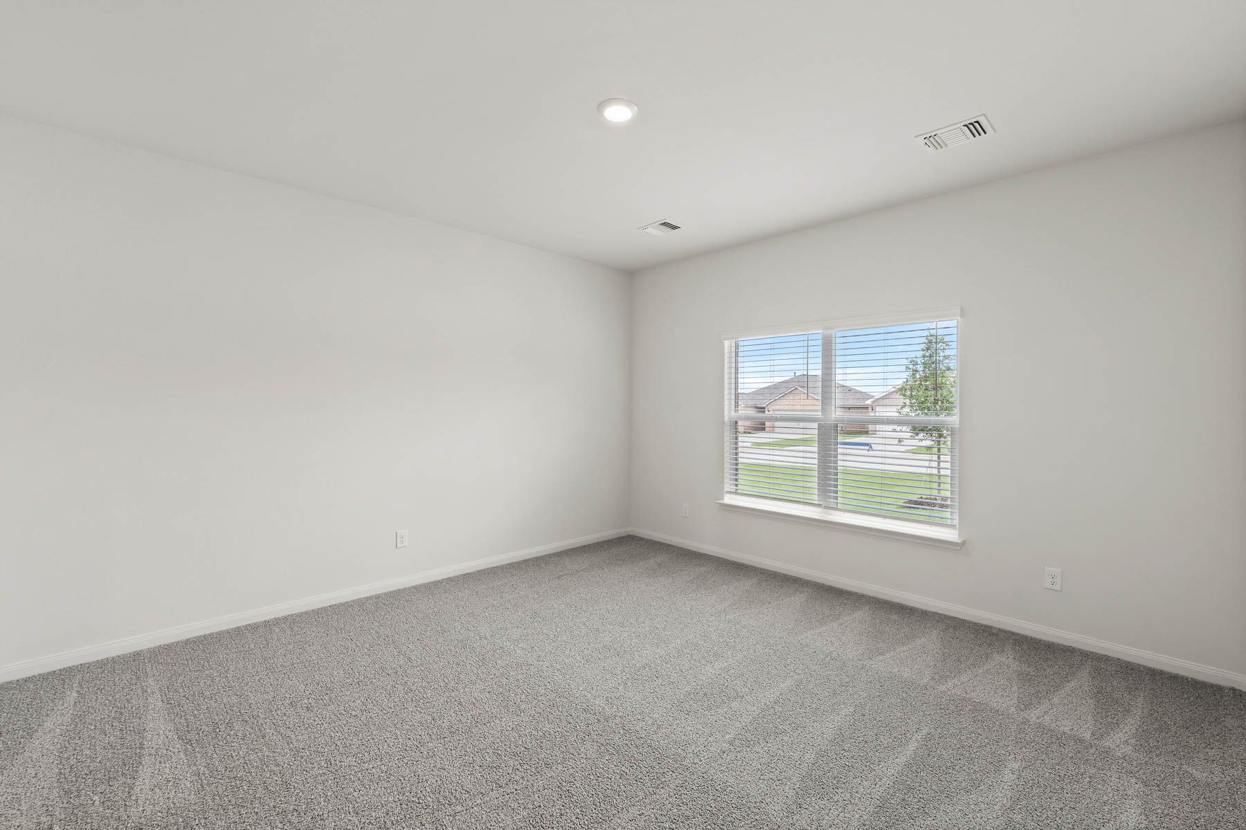 The large master bedroom has a window that lets in natural light and backyard views.