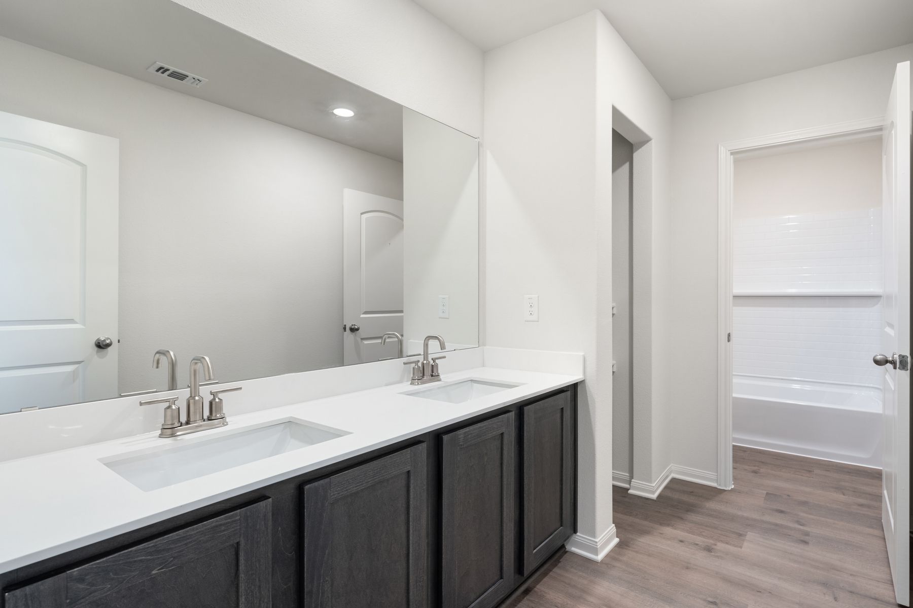 The secondary bathroom has a large vanity space and shower tub combo.