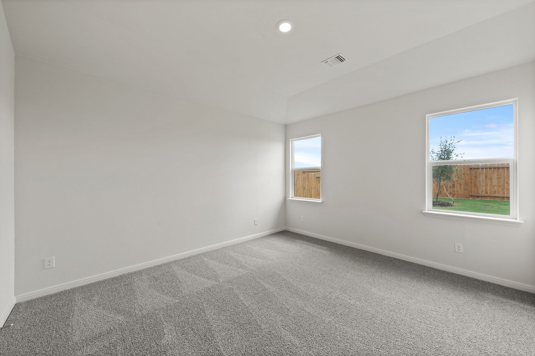 The spacious master bedroom has a large window that lets in natural light and backyard views.
