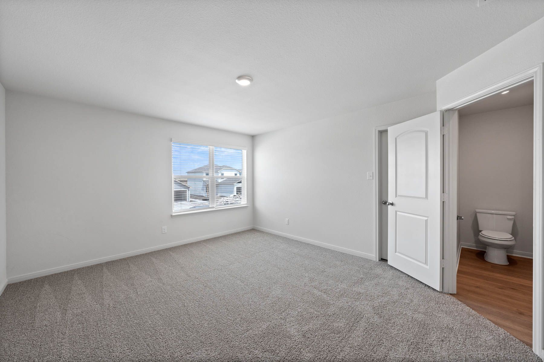 The spacious master bedroom has a large window that lets in natural light and backyard views.