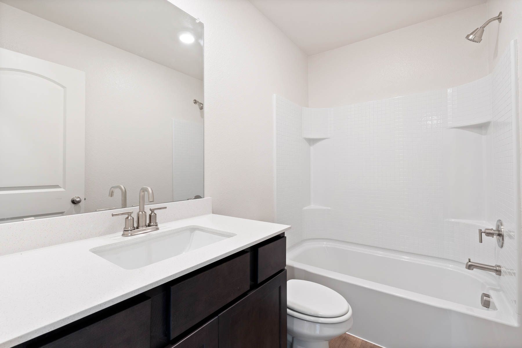 The secondary bathroom has a large vanity space and a shower-tub combo.