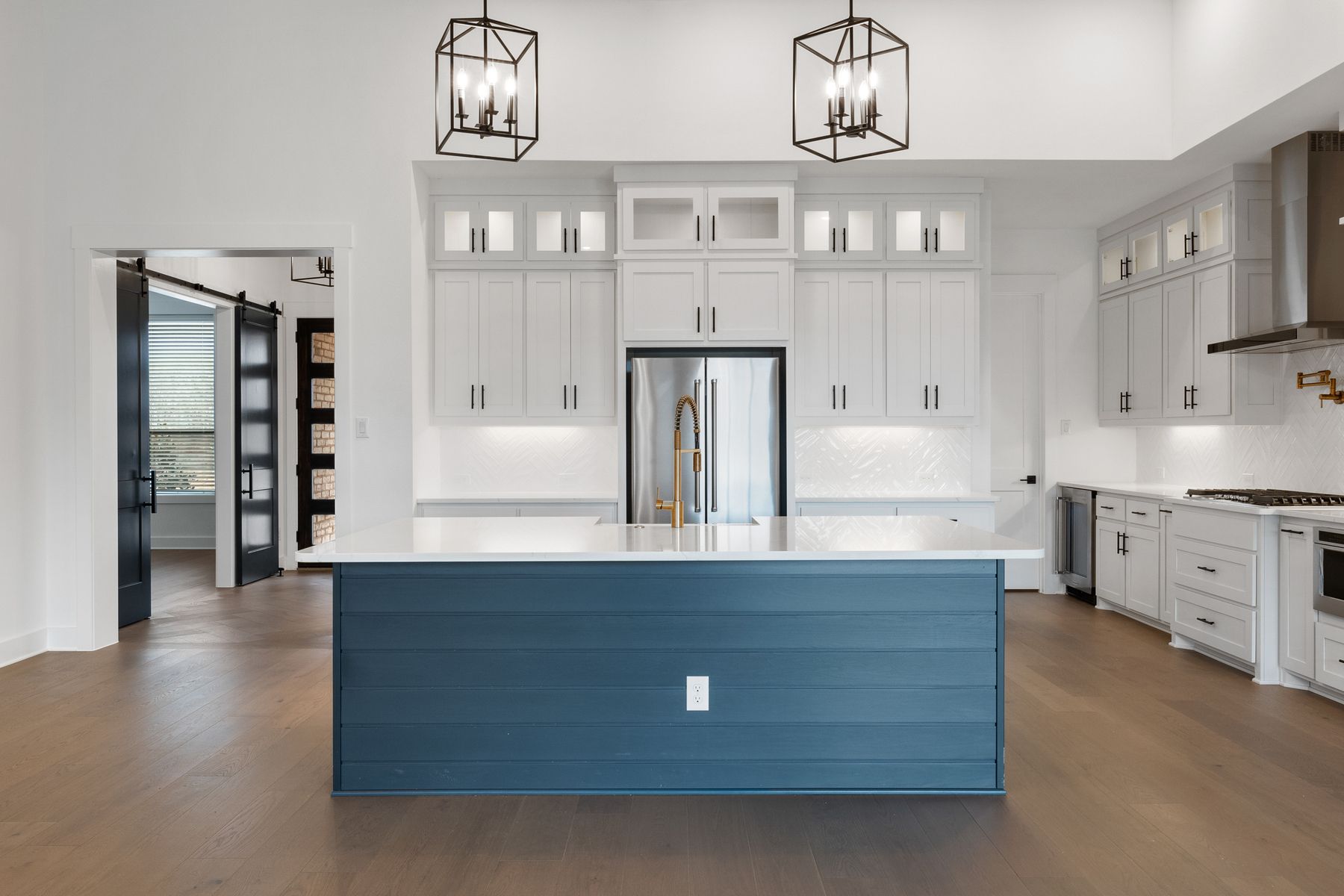 The kitchen has a beautiful blue island with quartz countertops.