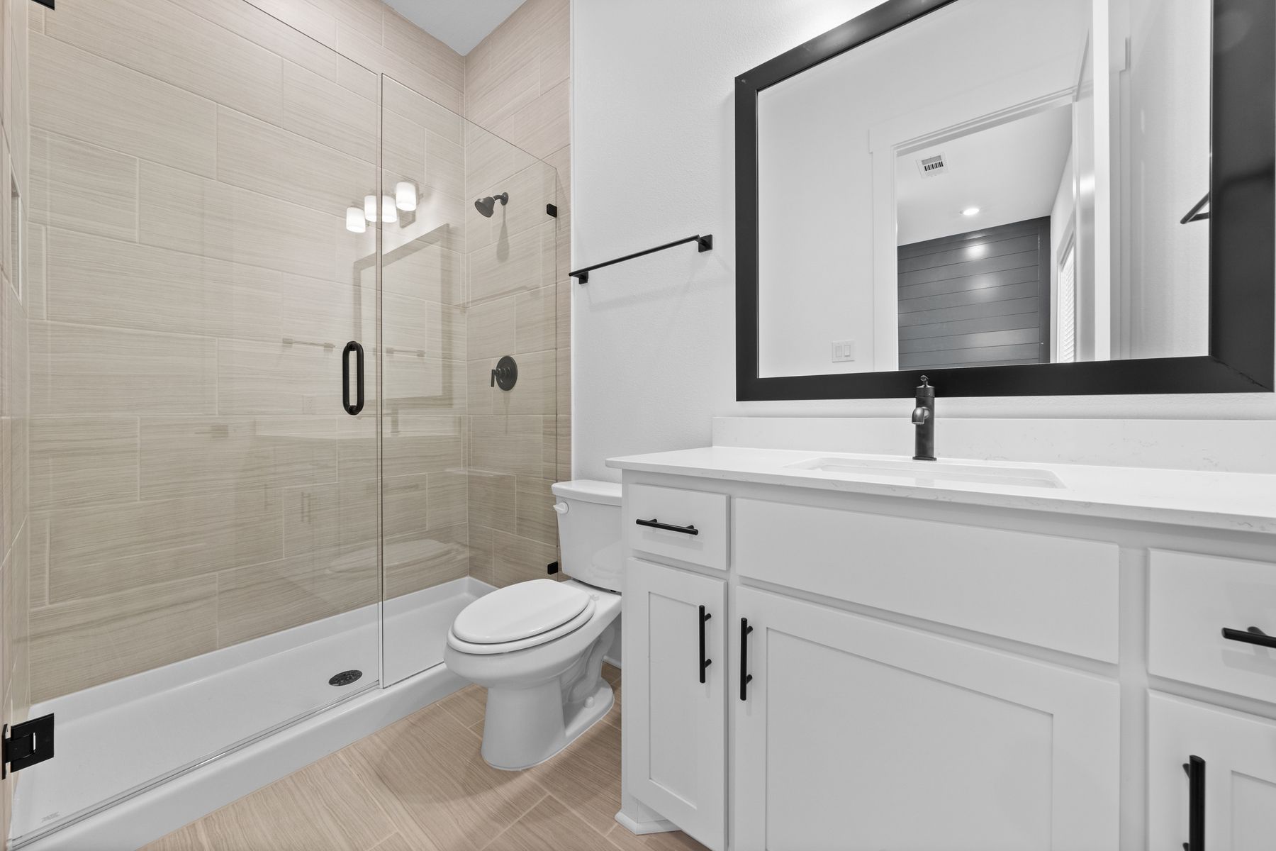 The secondary bathroom has a large vanity and glass, walk-in shower.