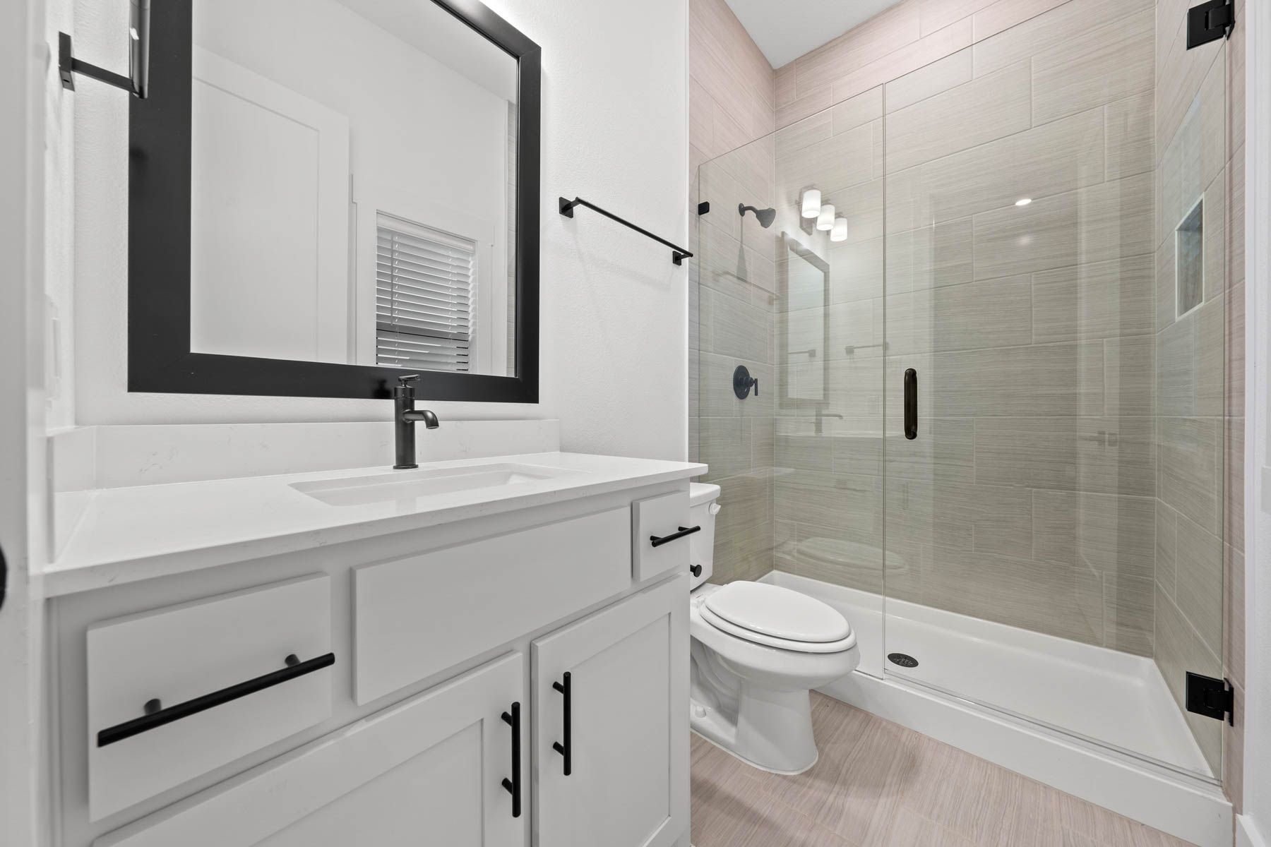 The secondary bathroom has a large vanity with plenty of cabinet space and a glass, walk-in shower.