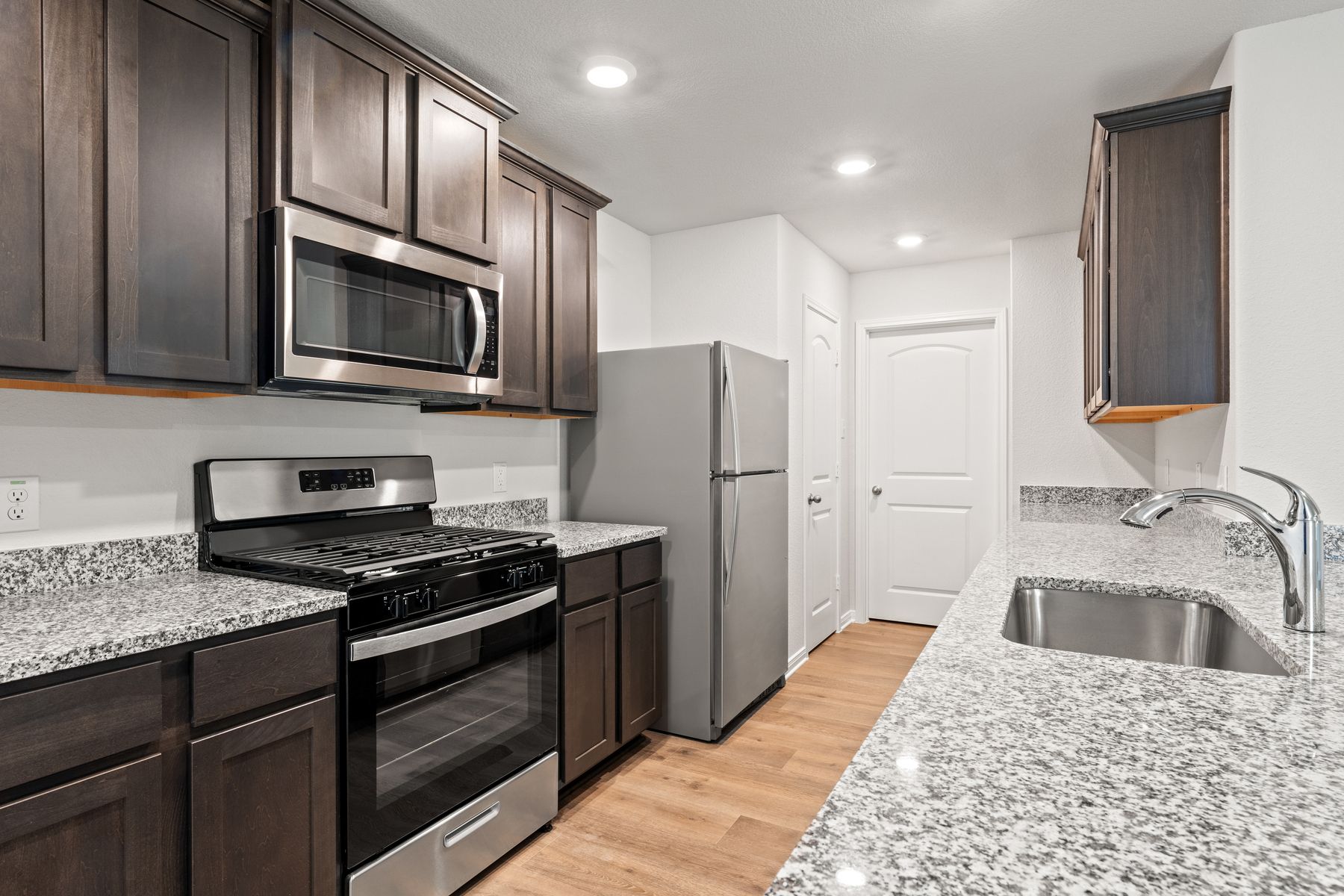 The kitchen of the Cedar has beautiful wood cabinetry and sprawling granite countertops.
