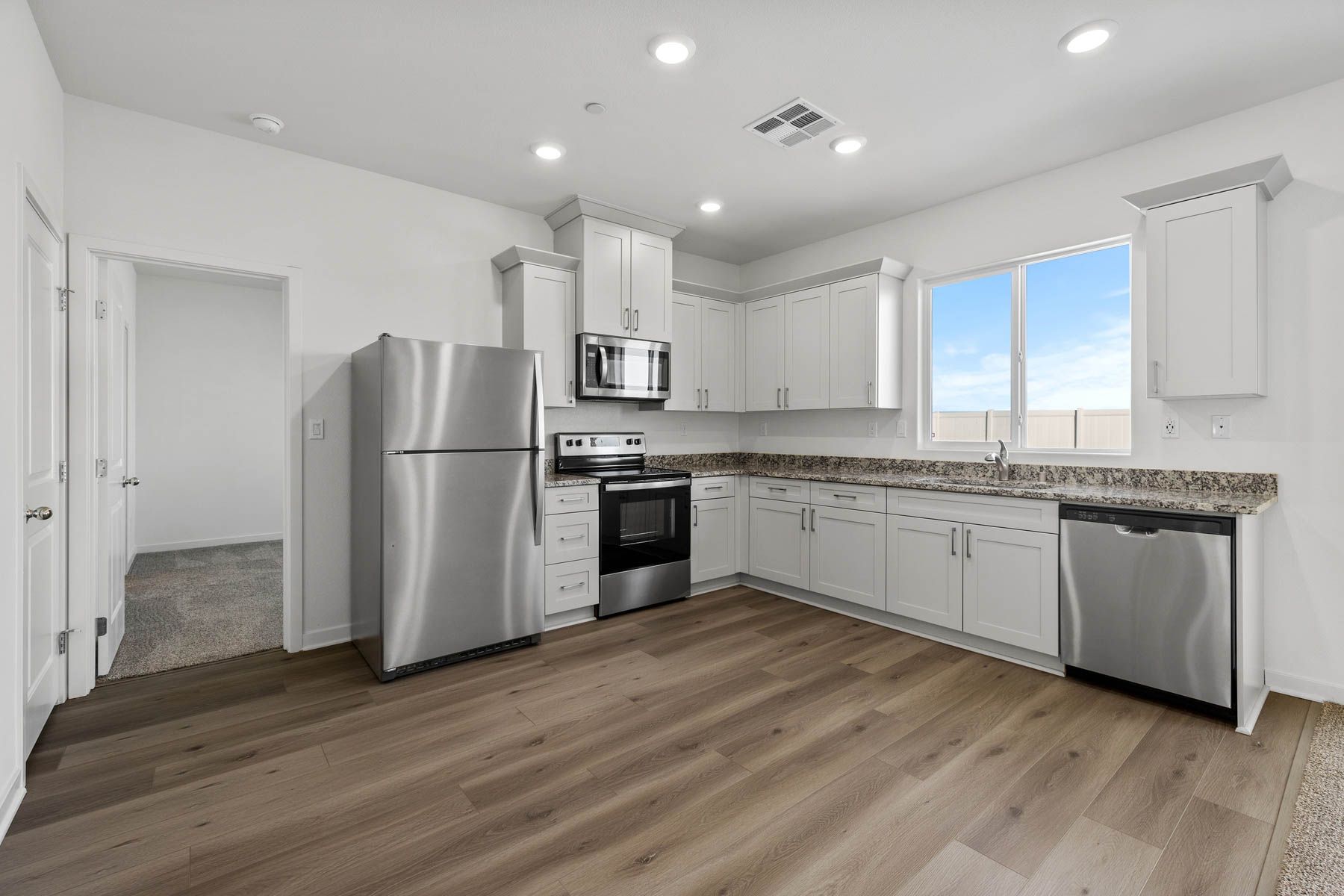 The kitchen has stainless steel appliances and plank flooring.