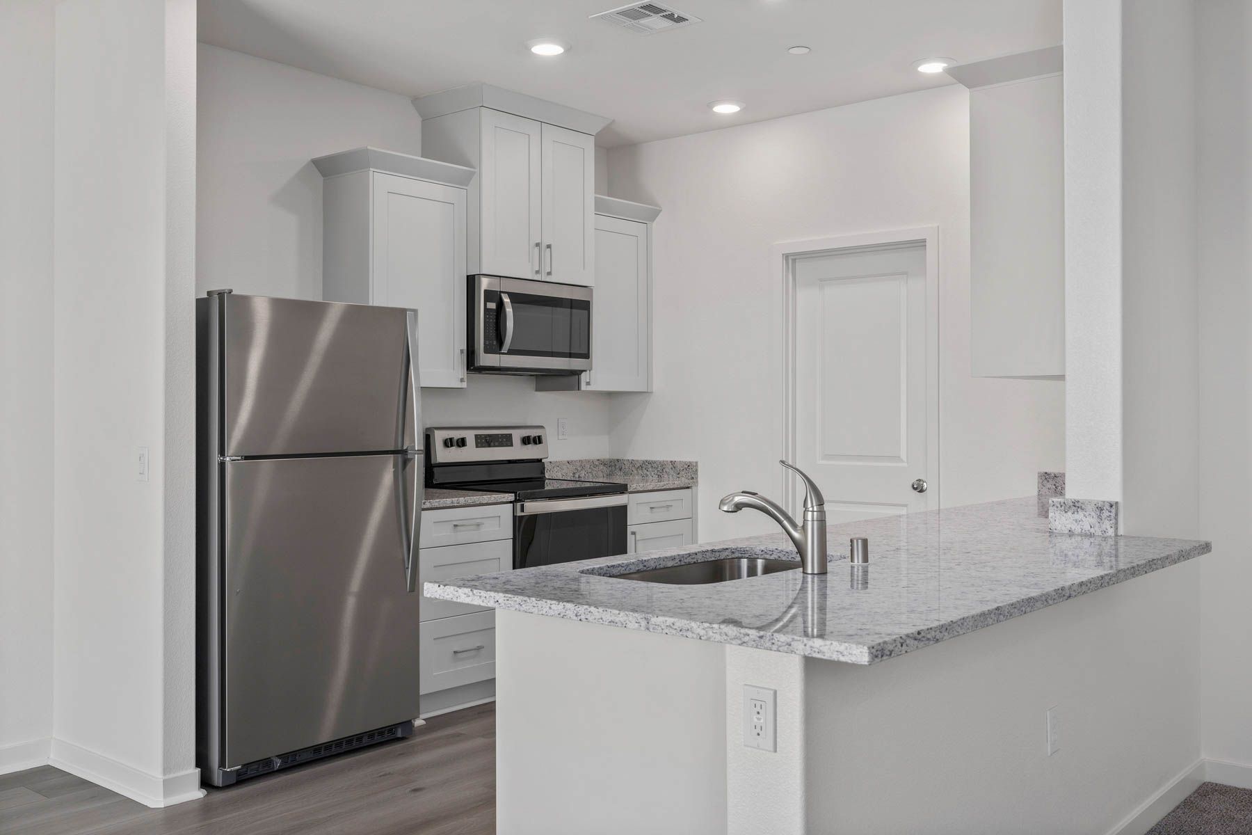 The kitchen has stainless steel appliances and plank flooring.