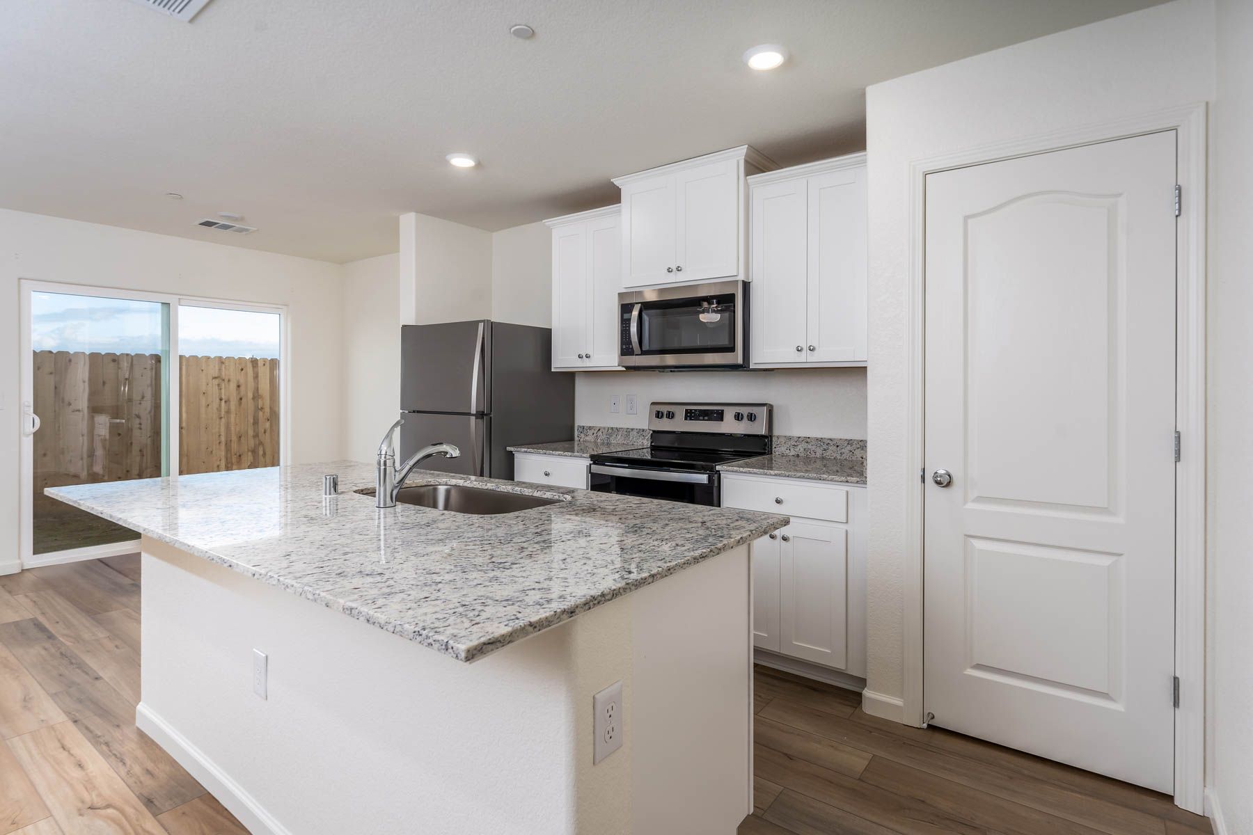 The kitchen has stainless steel appliances and plank flooring.