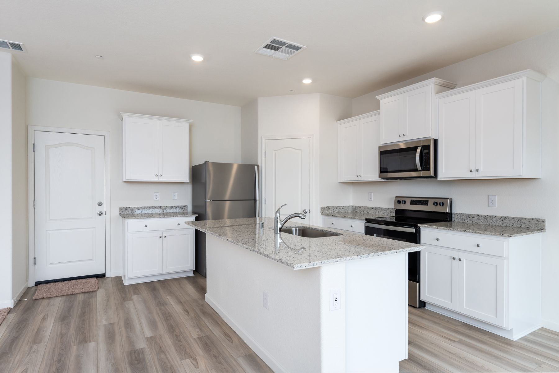 The kitchen has stainless steel appliances and plank flooring.
