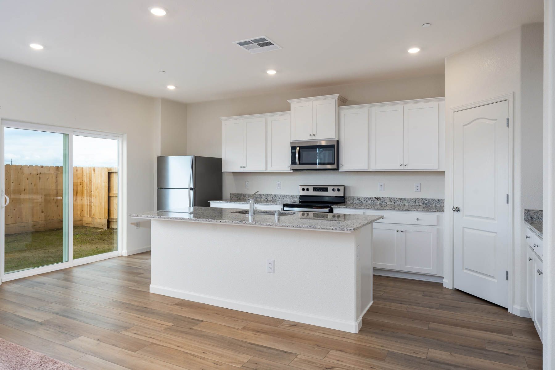 The kitchen has stainless steel appliances and plank flooring.