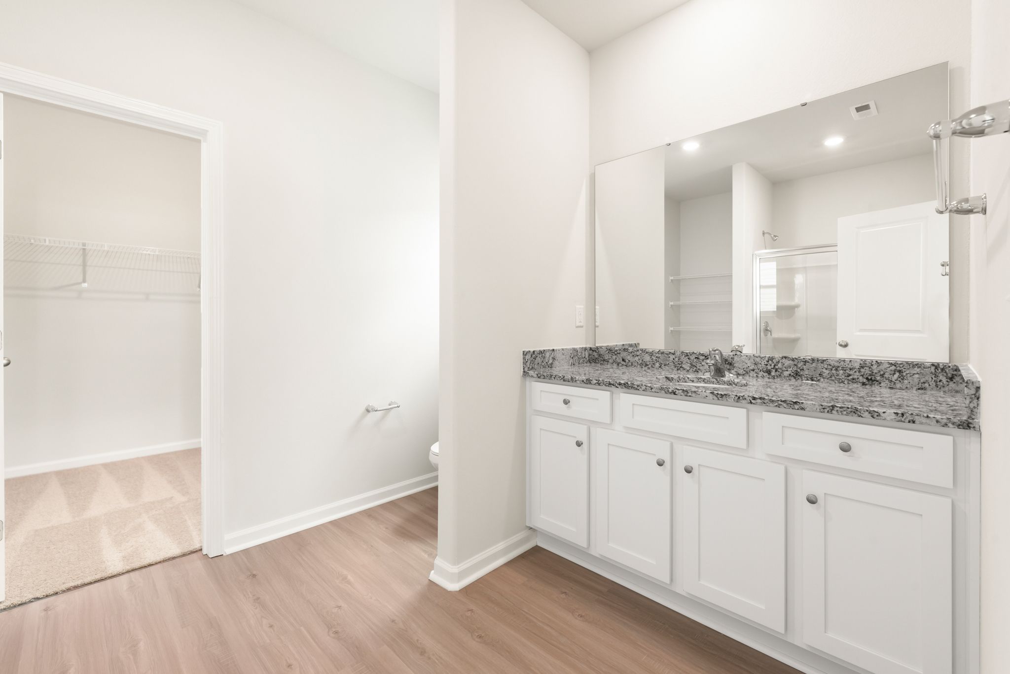This bathroom has granite countertops and a glass-enclosed shower