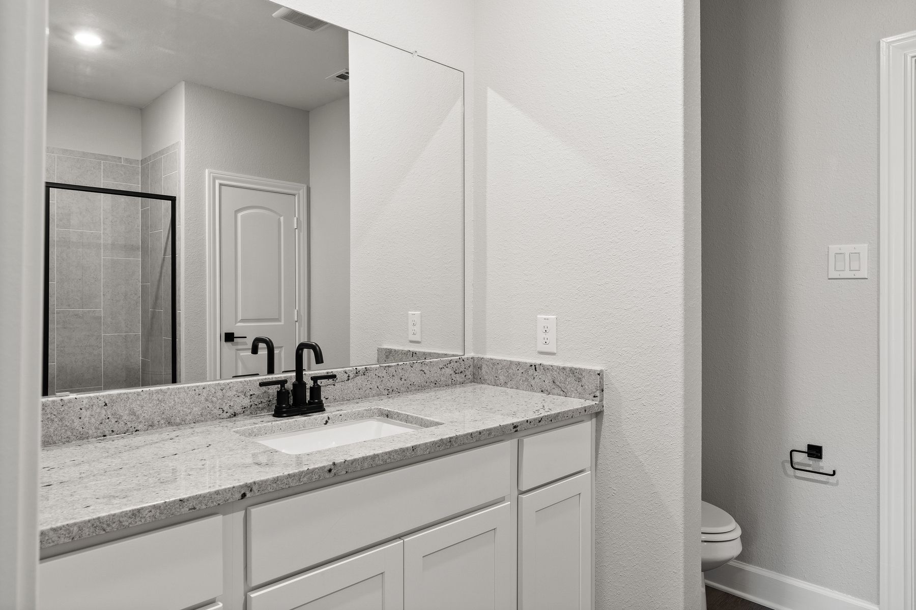 The master bathroom of the Sabine floor plan has a large vanity space with sprawling granite countertops.
