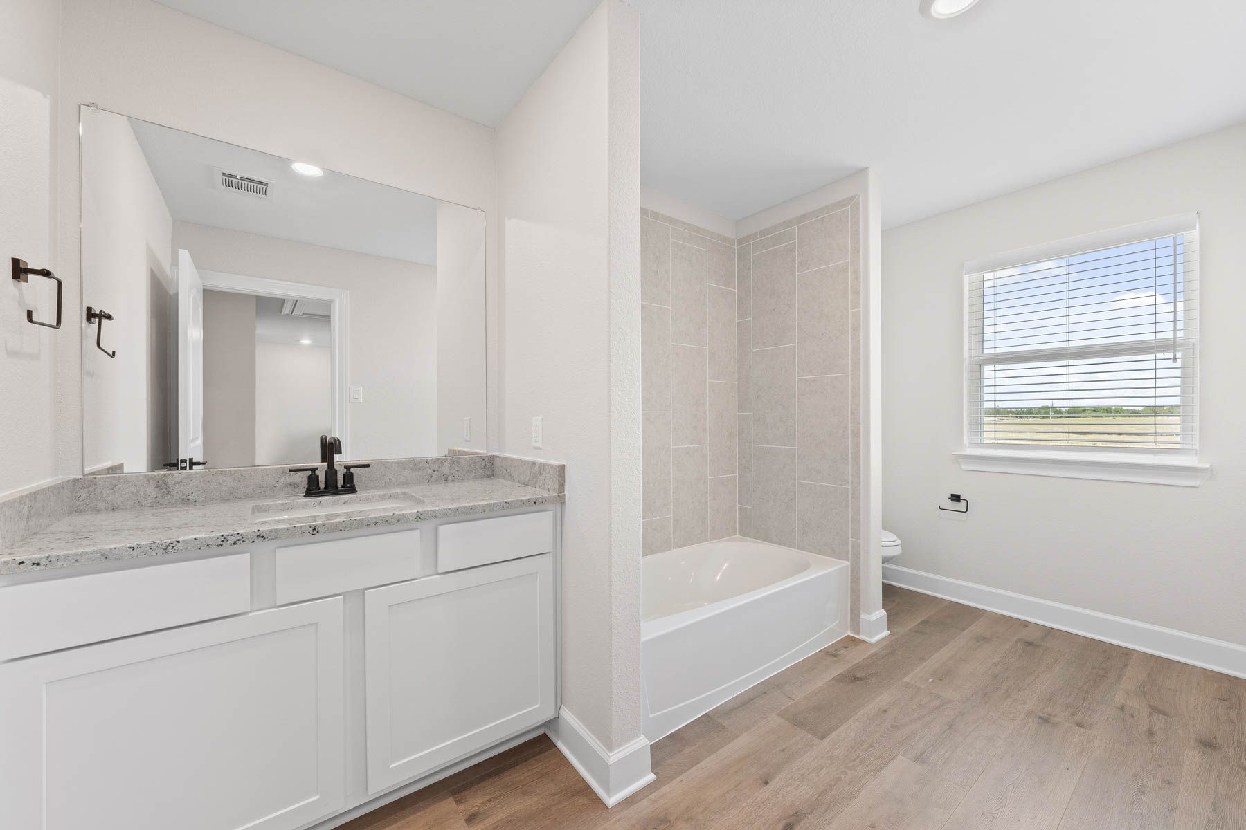 The secondary bathroom of the Cypress floor plan has a large vanity and shower-tub combo.