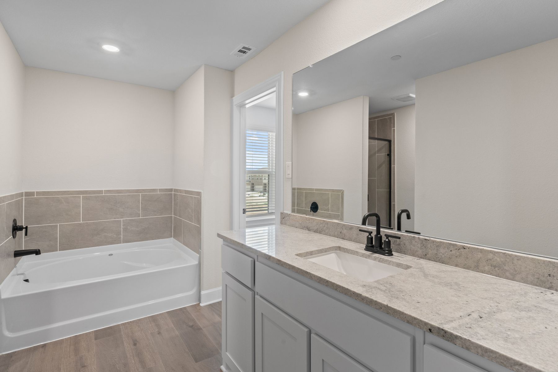 The master bathroom has a garden tub and glass, walk-in shower.