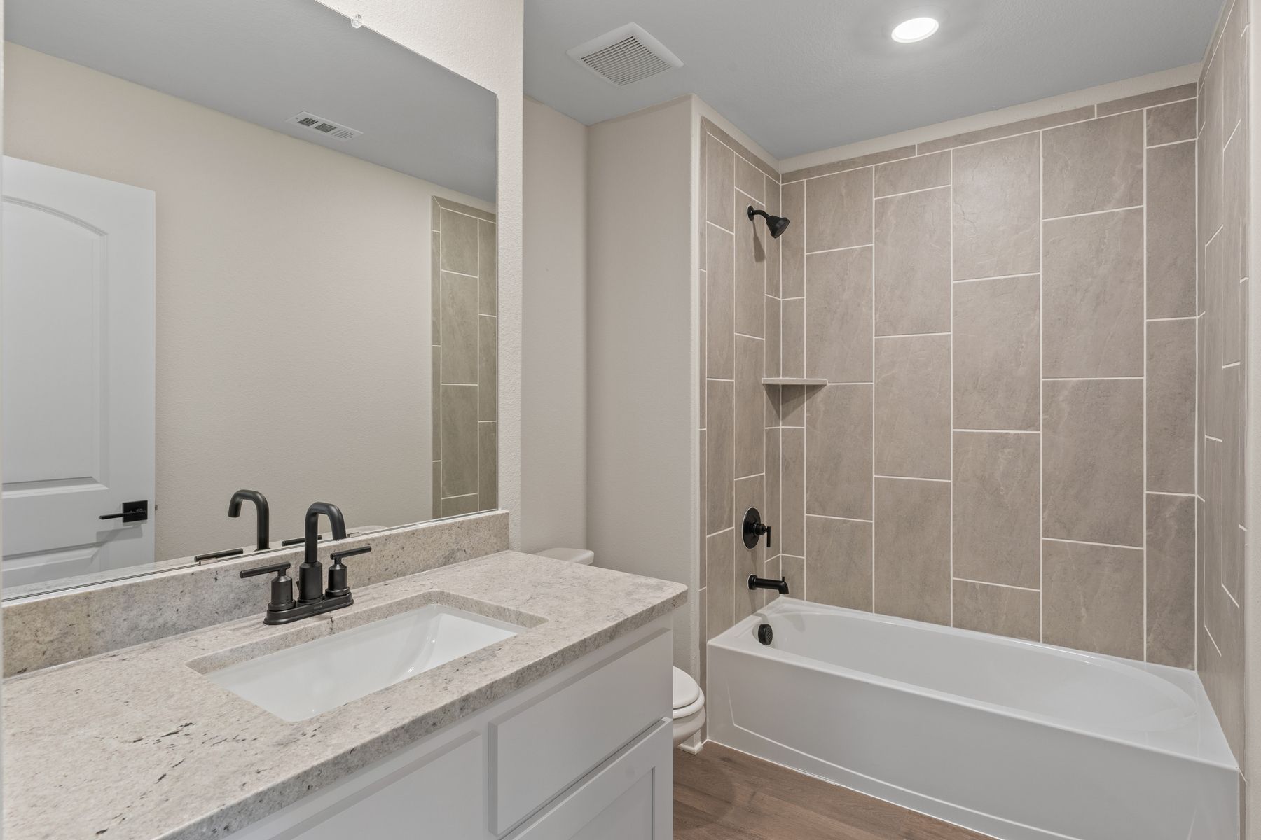 The secondary bathroom has a large vanity space and a shower-tub combo.