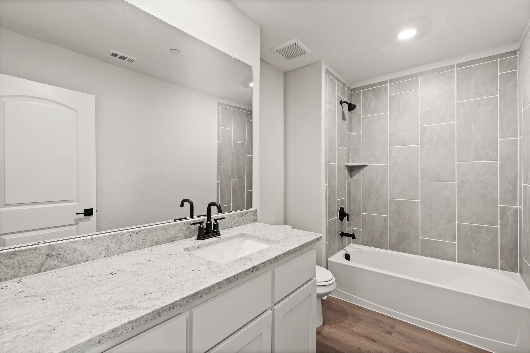 The secondary bathroom has a large vanity space and shower-tub combo.