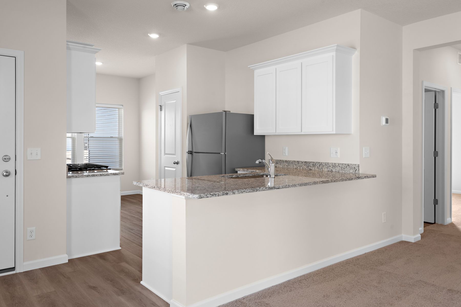 The kitchen has stainless steel appliances and plank flooring.