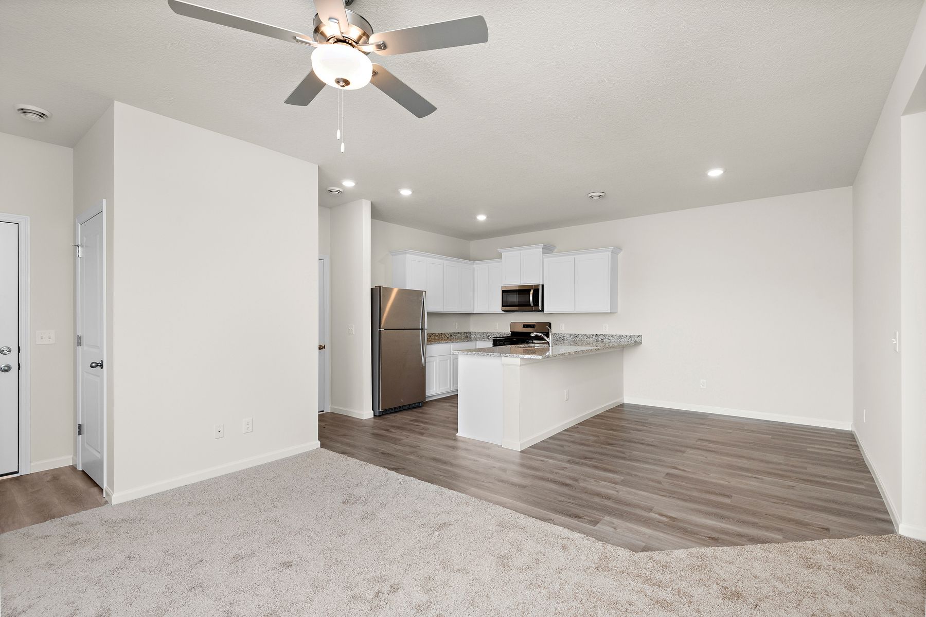 The kitchen has stainless steel appliances and plank flooring.