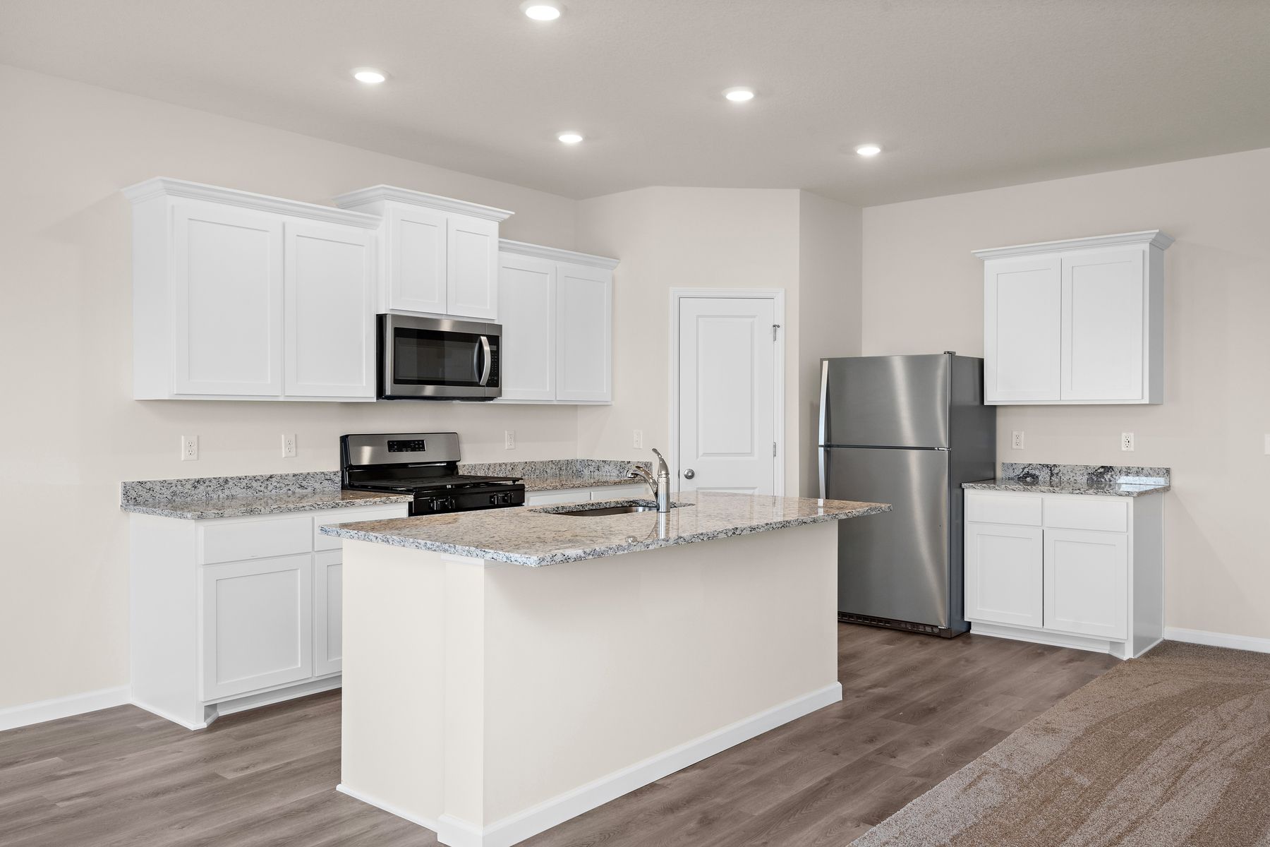 The kitchen has stainless steel appliances and plank flooring.