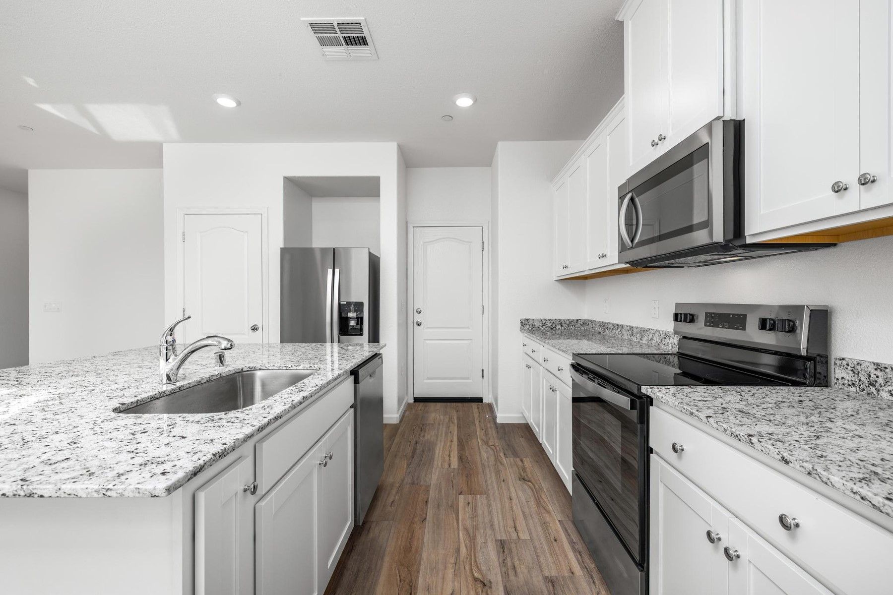 The kitchen has stainless steel appliances and plank flooring.