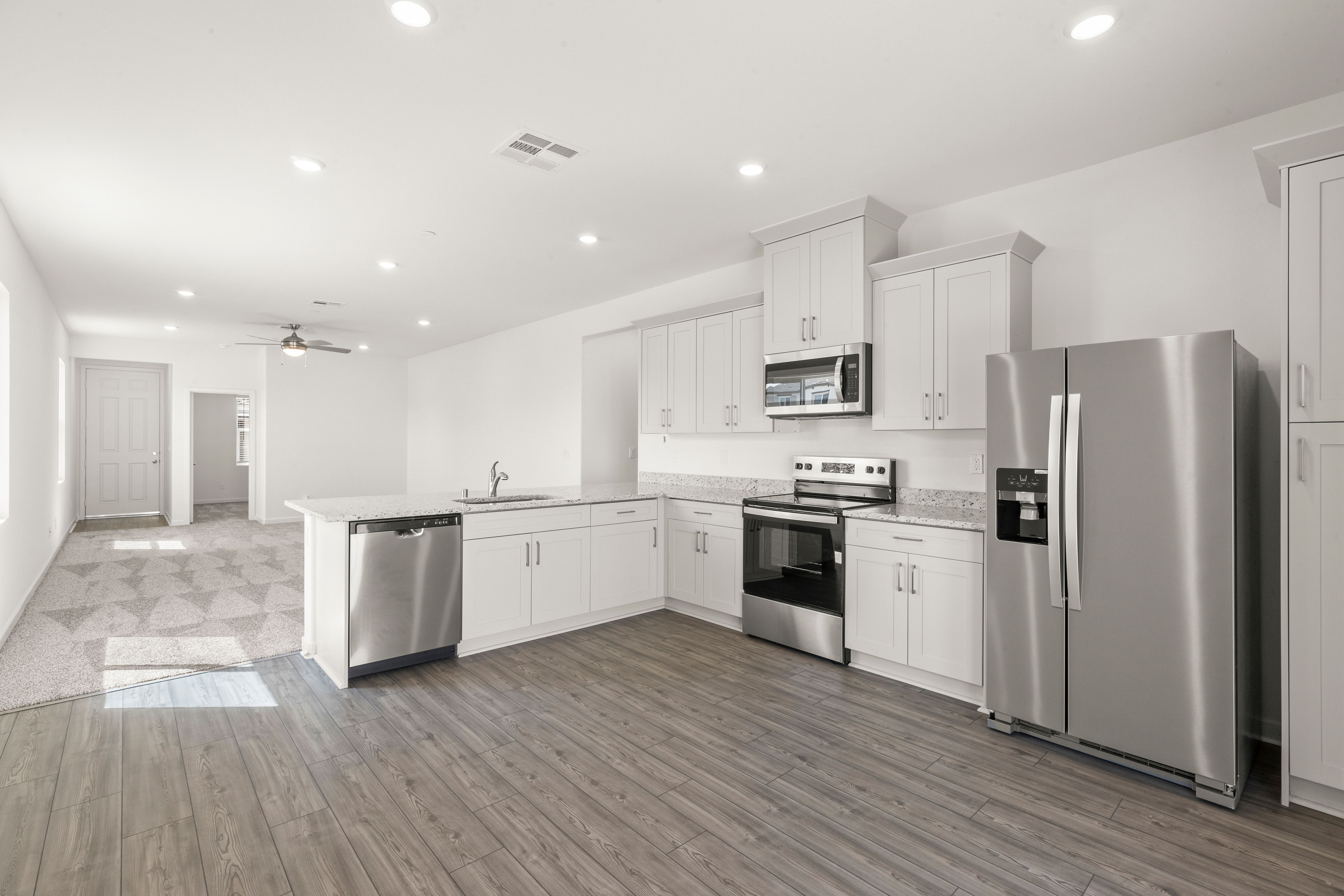 The kitchen has stainless steel appliances and plank flooring.