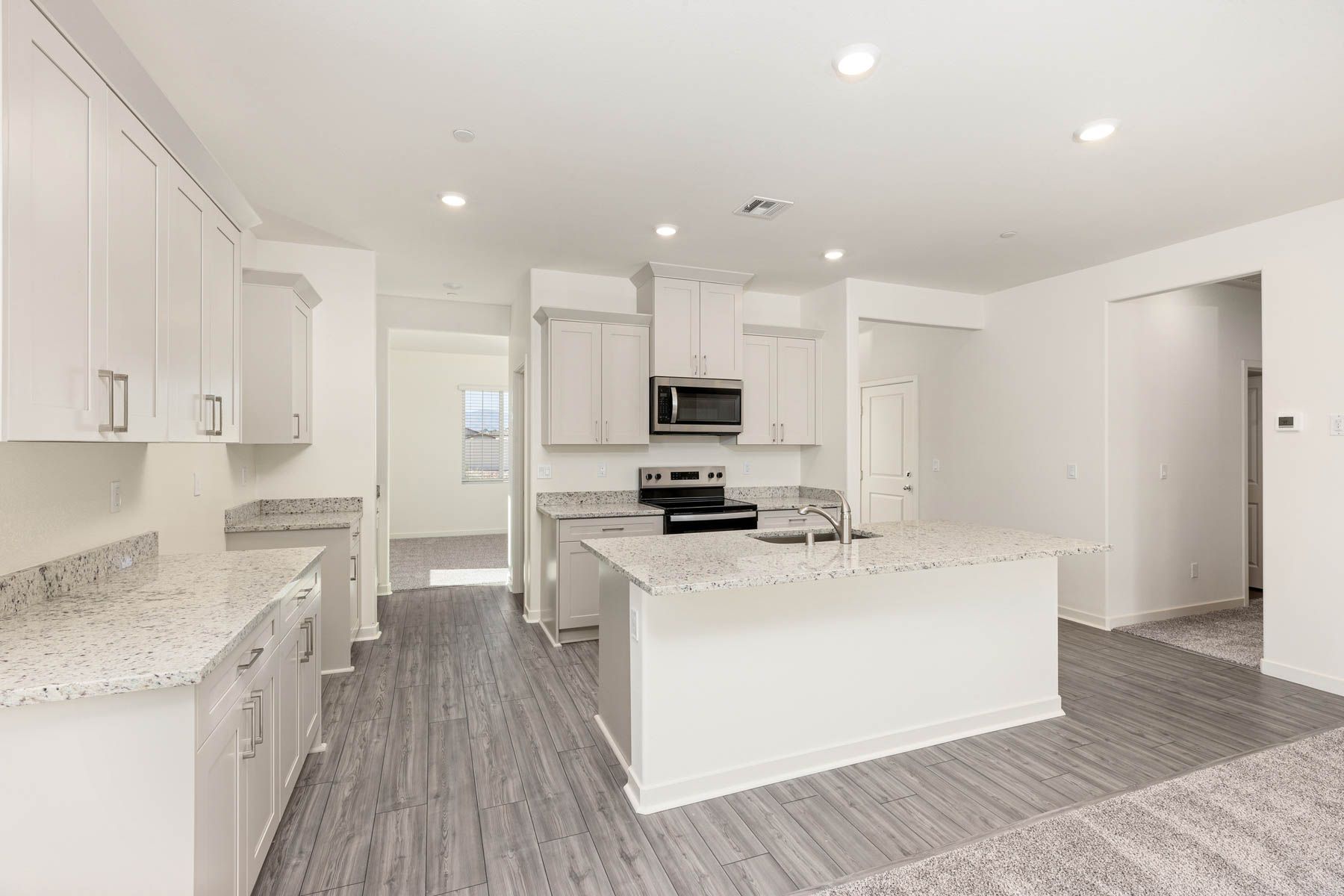 The kitchen has stainless steel appliances and plank flooring.
