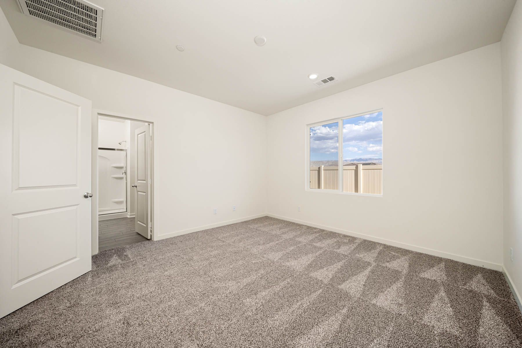 The master bedroom is spacious and has carpet.
