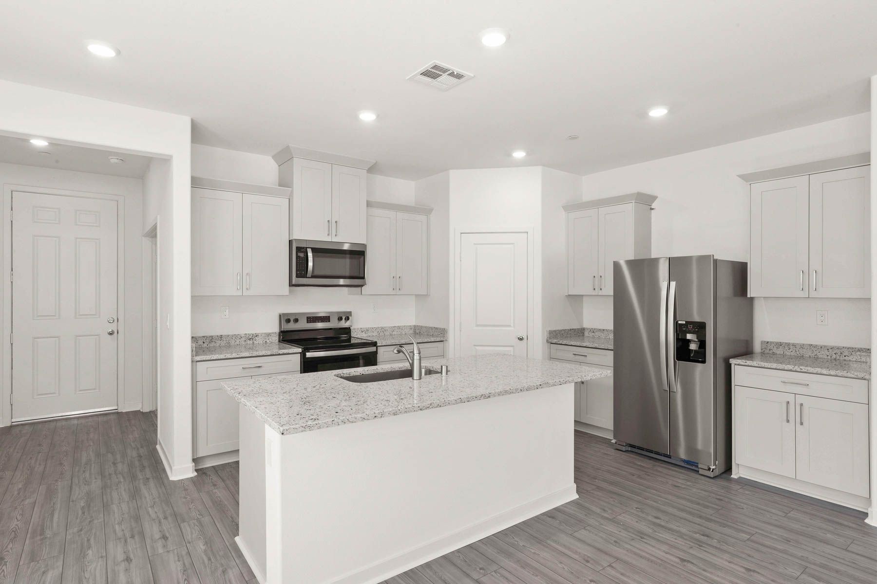 The kitchen has stainless steel appliances and plank flooring.