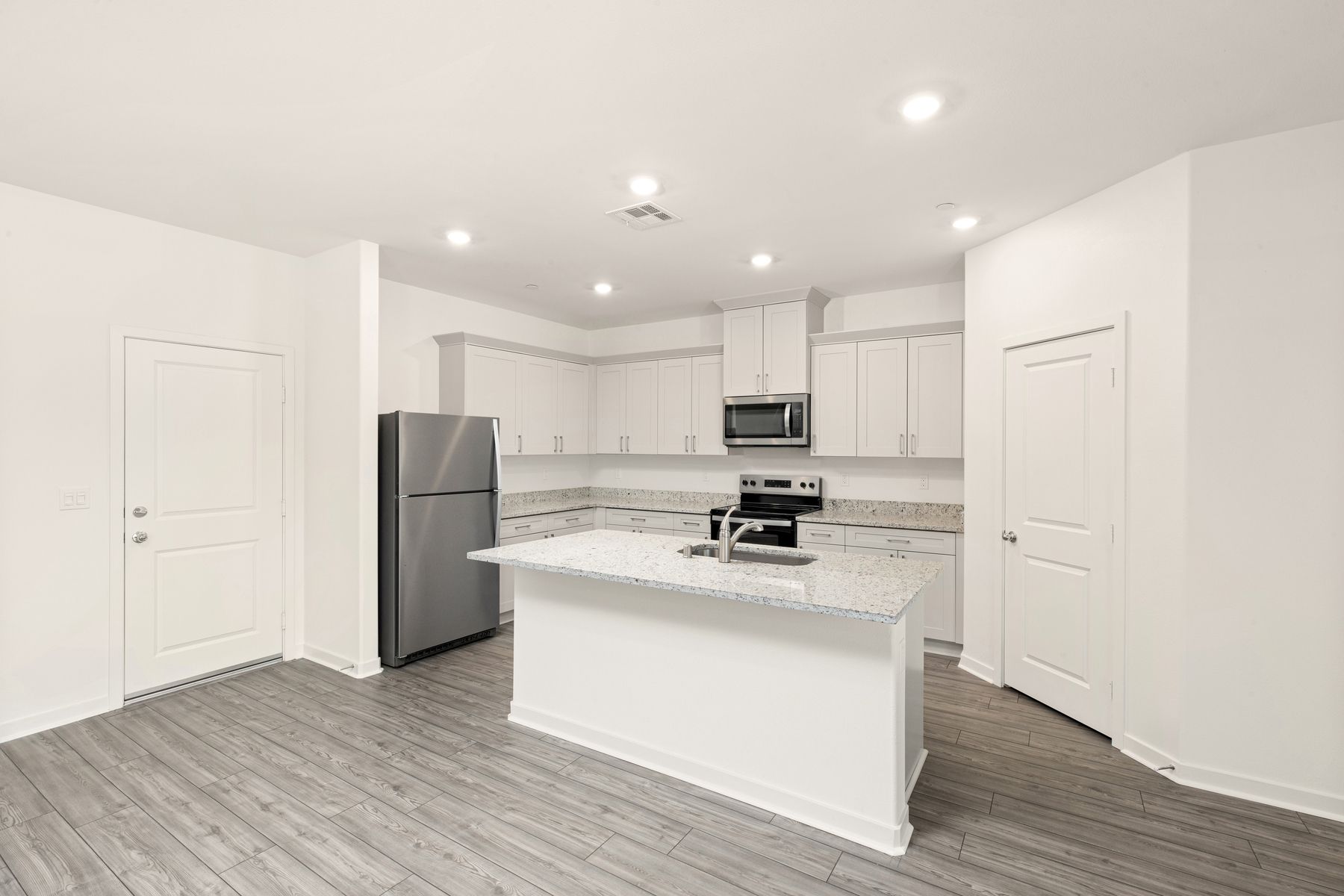 The kitchen has stainless steel appliances and plank flooring.
