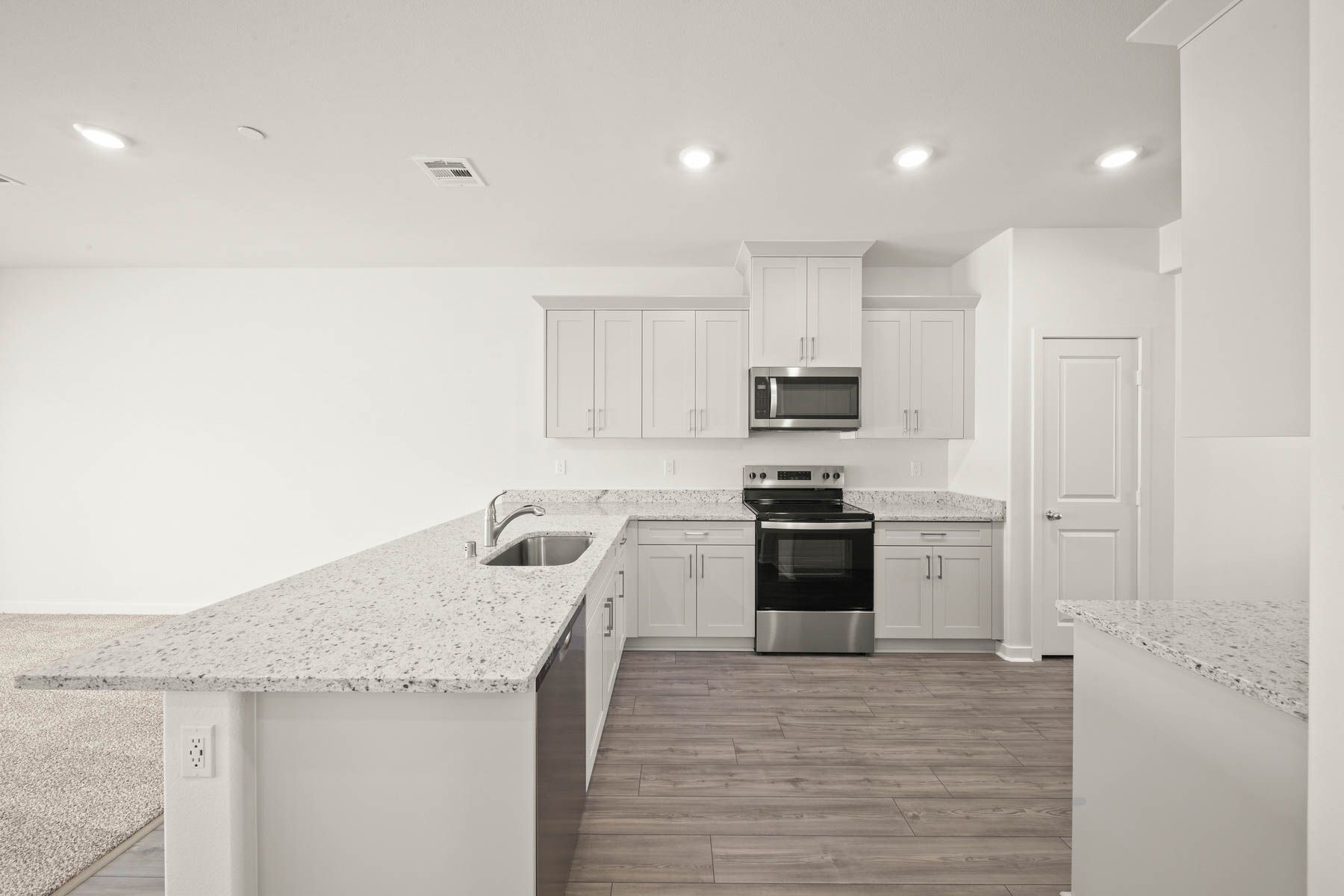 The kitchen has stainless steel appliances and plank flooring.