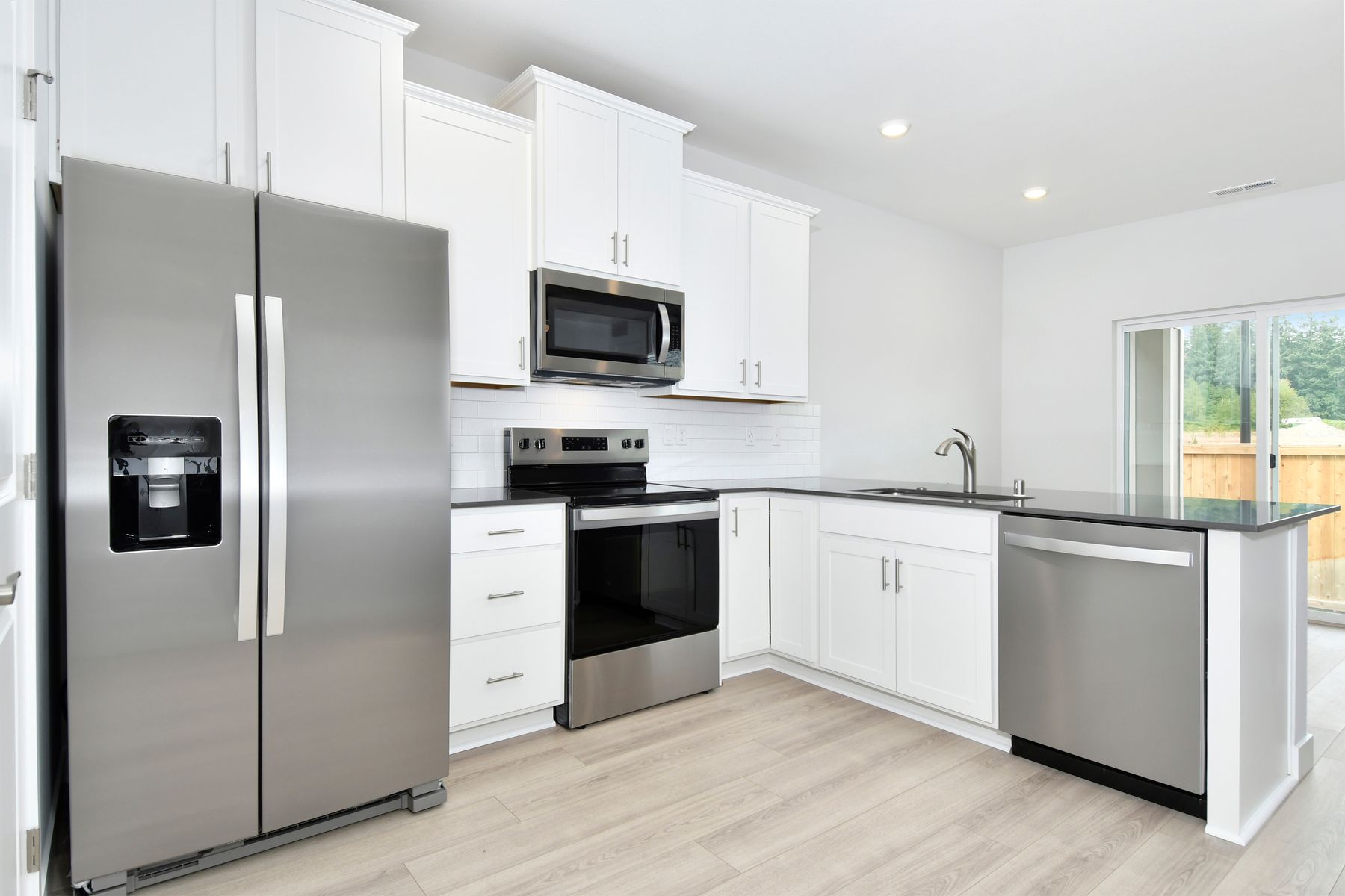 The kitchen has stainless steel appliances and plank flooring.