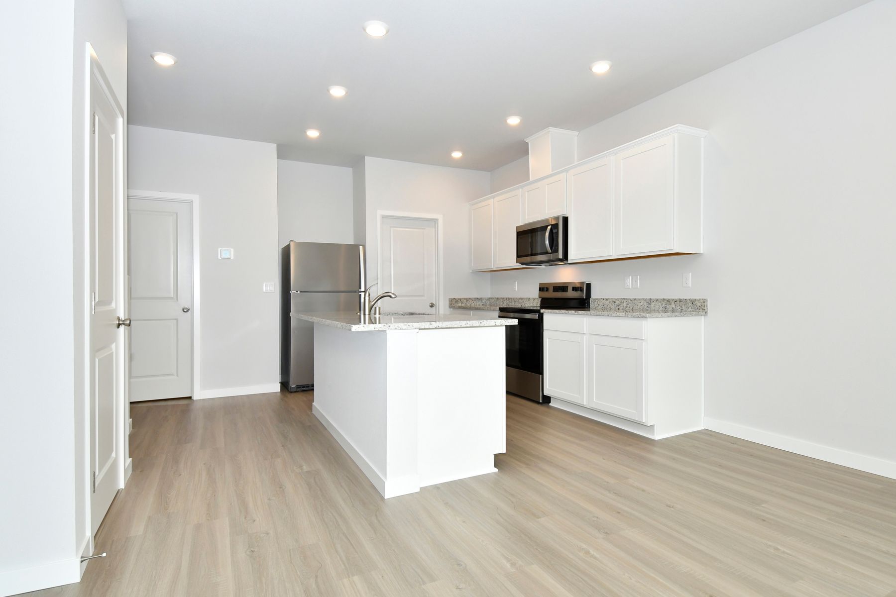 The kitchen has stainless steel appliances and plank flooring.