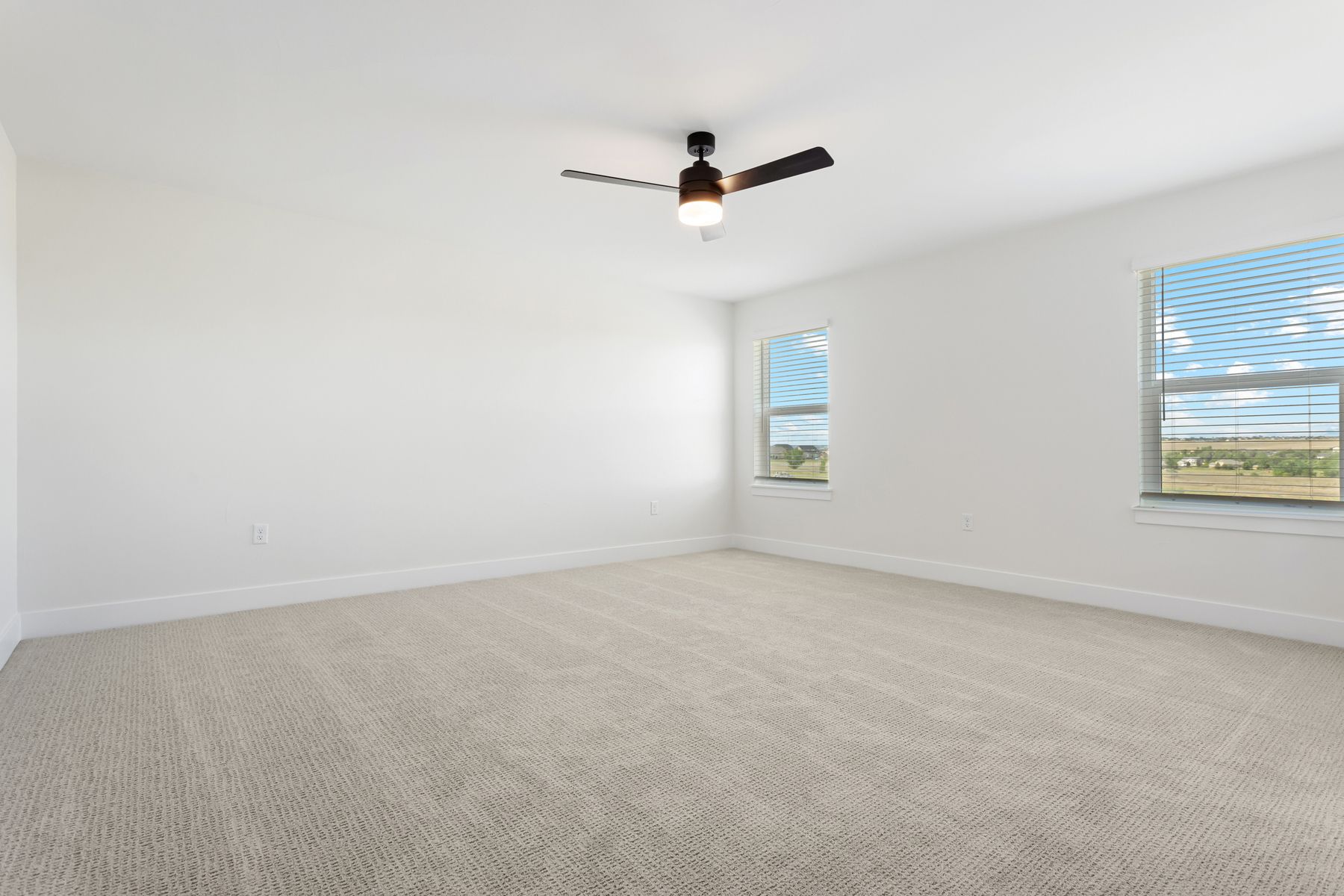 The master bedroom is spacious and has two large windows.