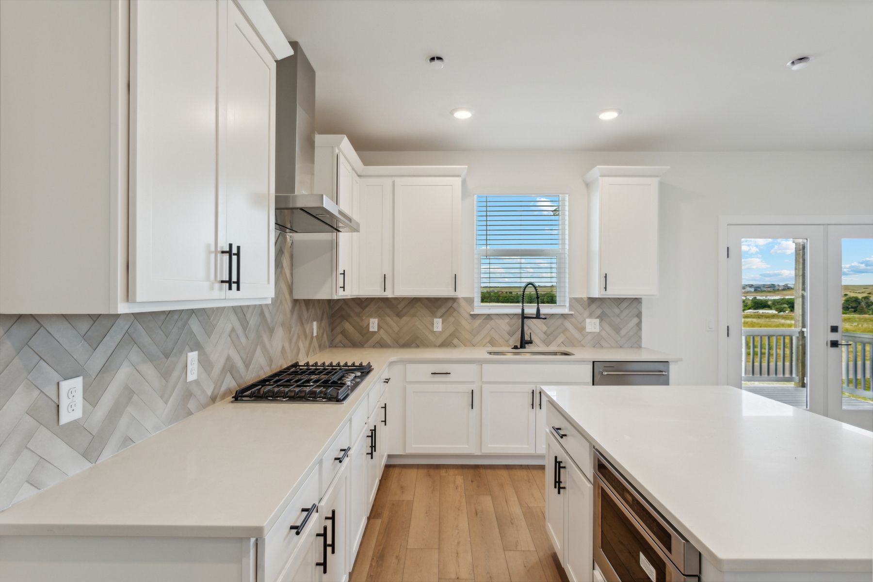 The kitchaThe kitchen has beautiful white cabinetry with black hardware.en has sprawling quartz countertops.