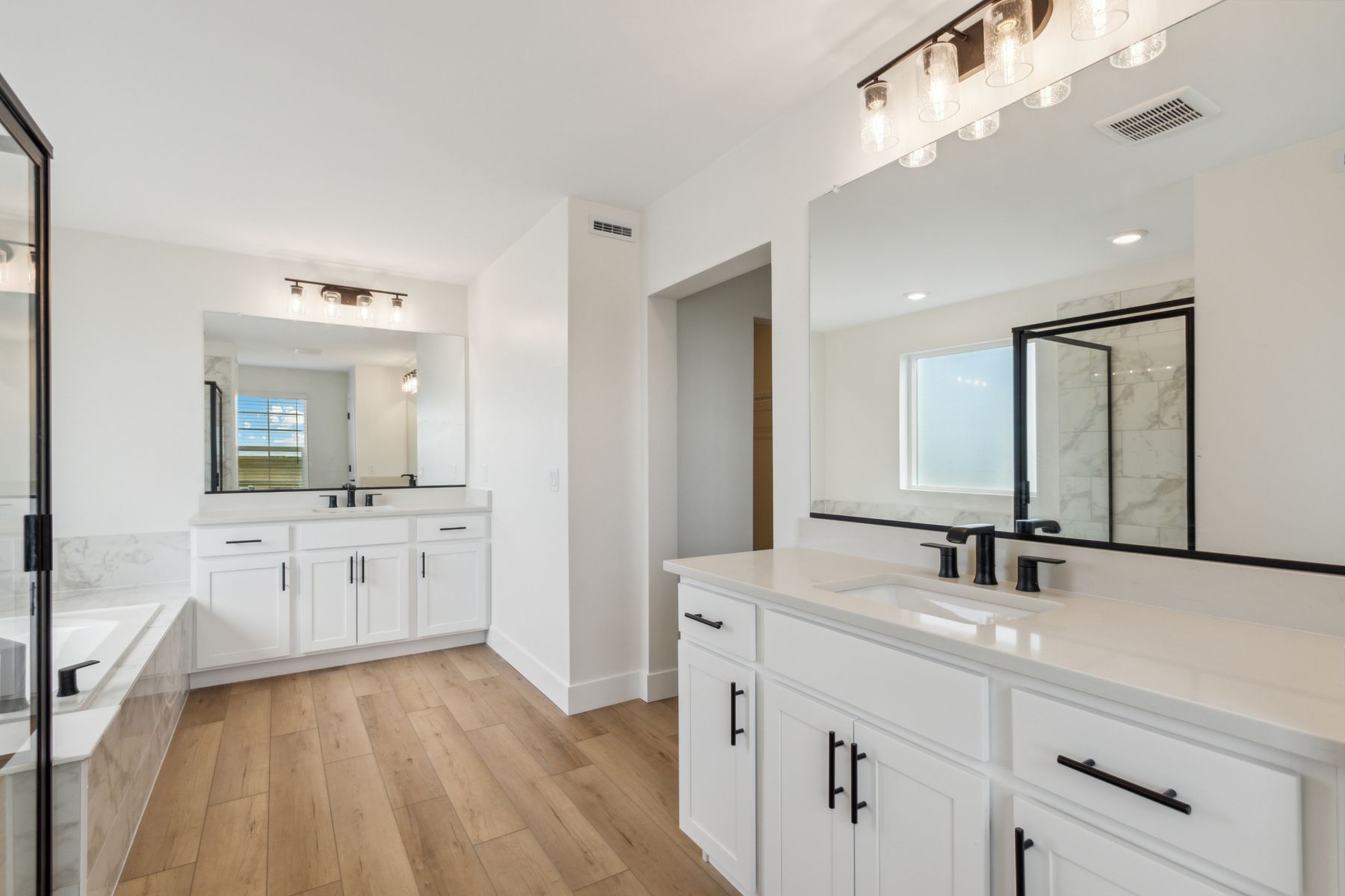 The spacious master bathroom has his-and-hers vanity spaces with quartz countertops.
