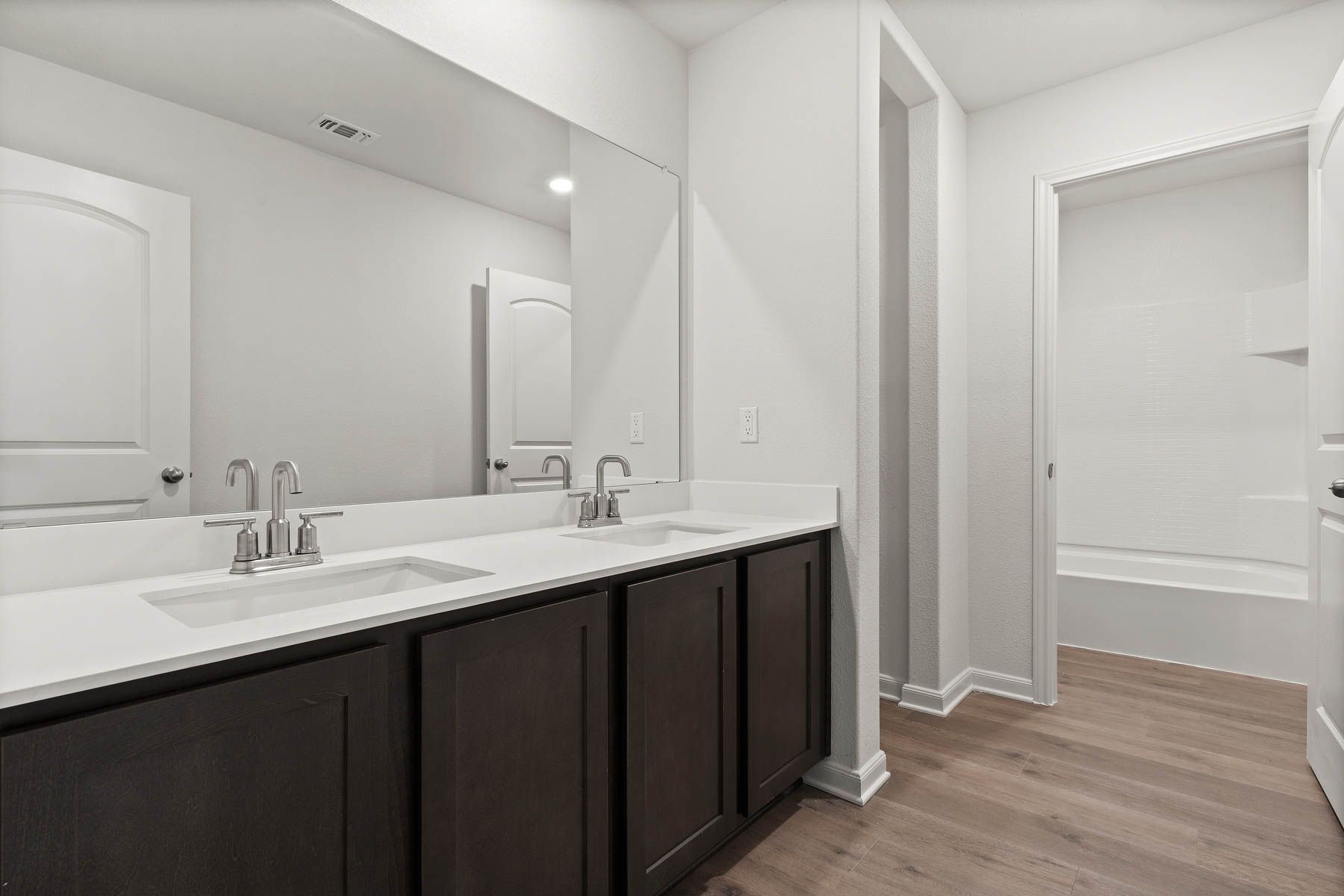 The secondary bathroom of the Driftwood has a large dual-sink vanity and shower-tub combo.