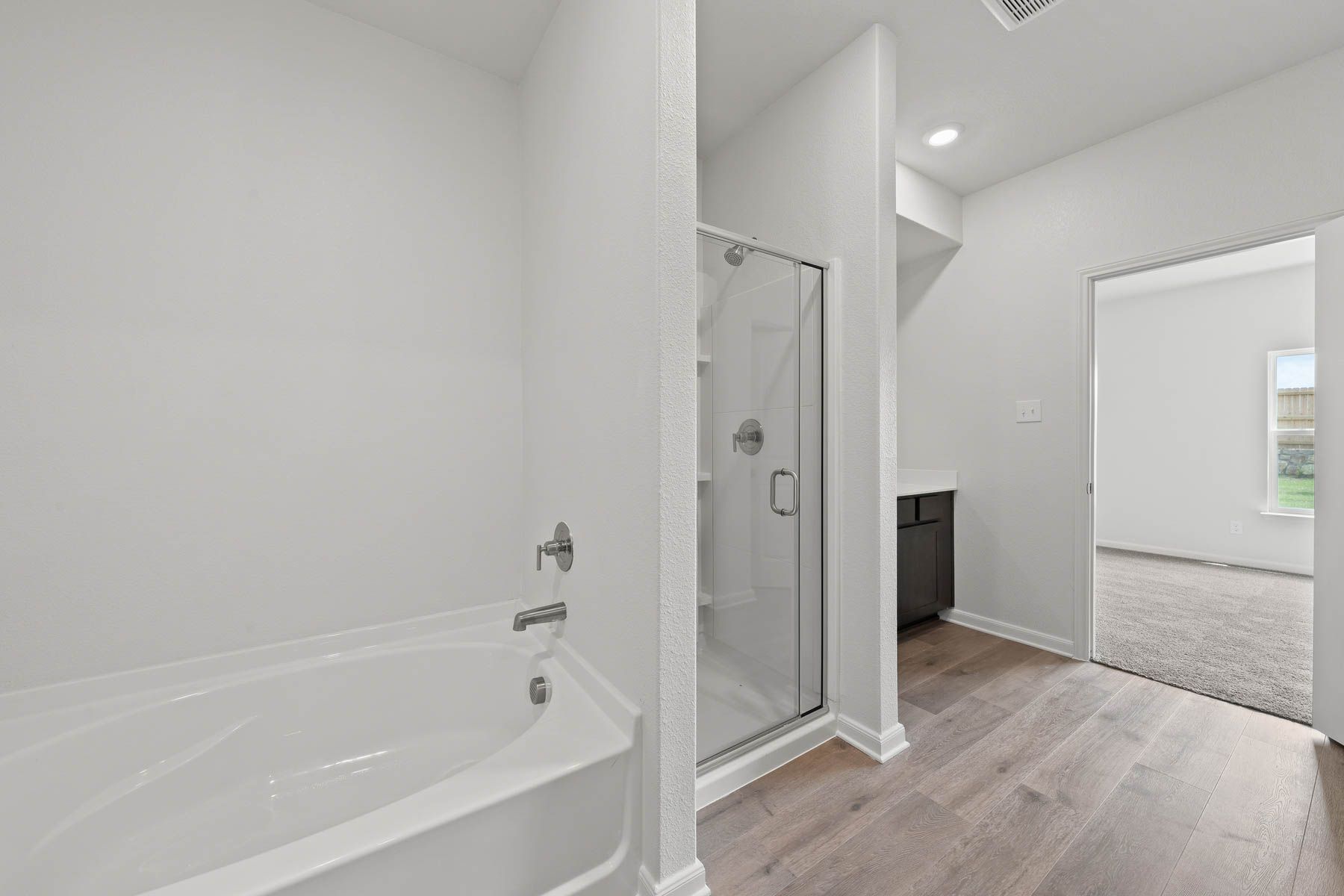 The master bathroom of the Driftwood plan has a glass walk-in shower and large garden tub.