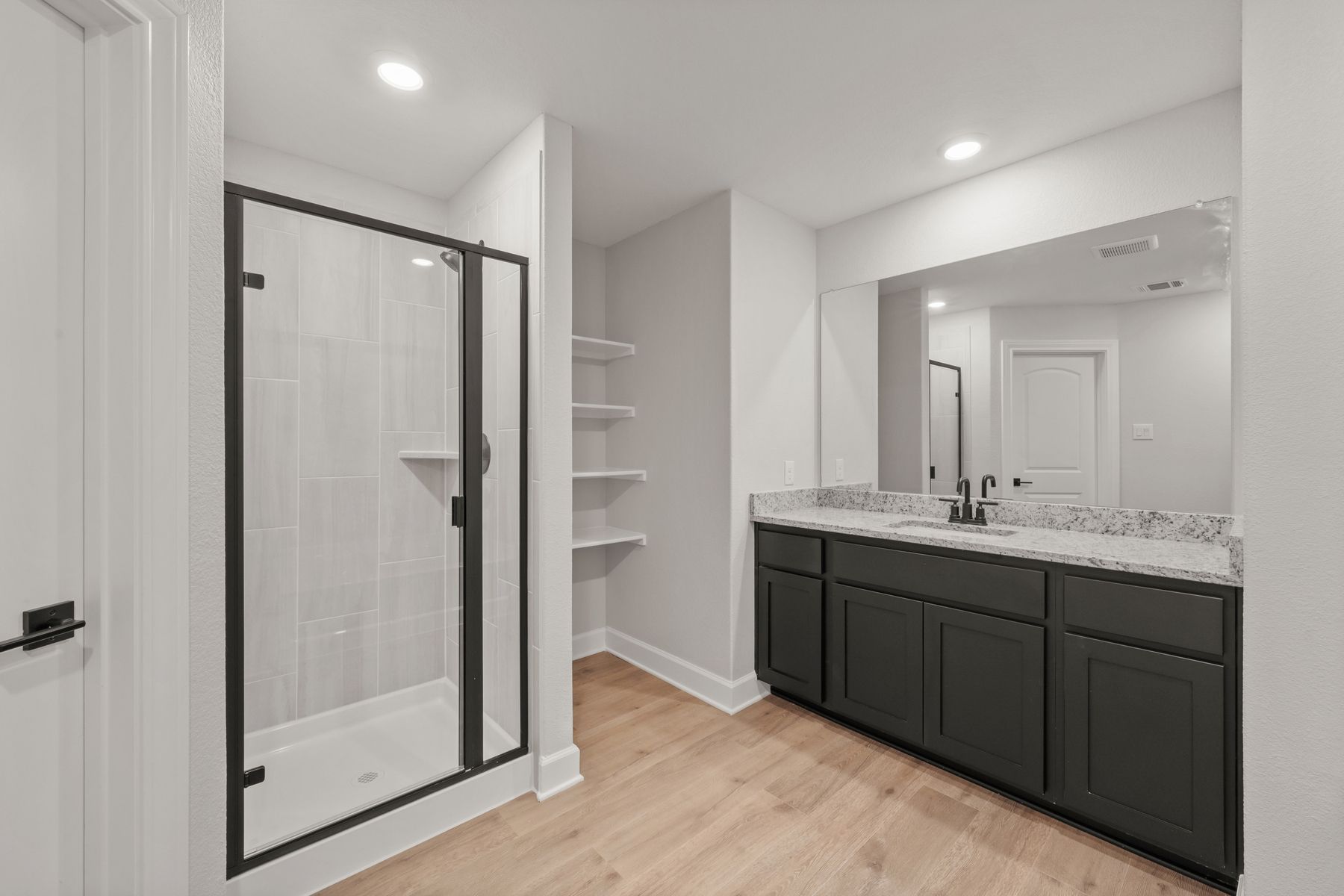 The master bathroom has a spacious vanity and a glass, walk-in shower.