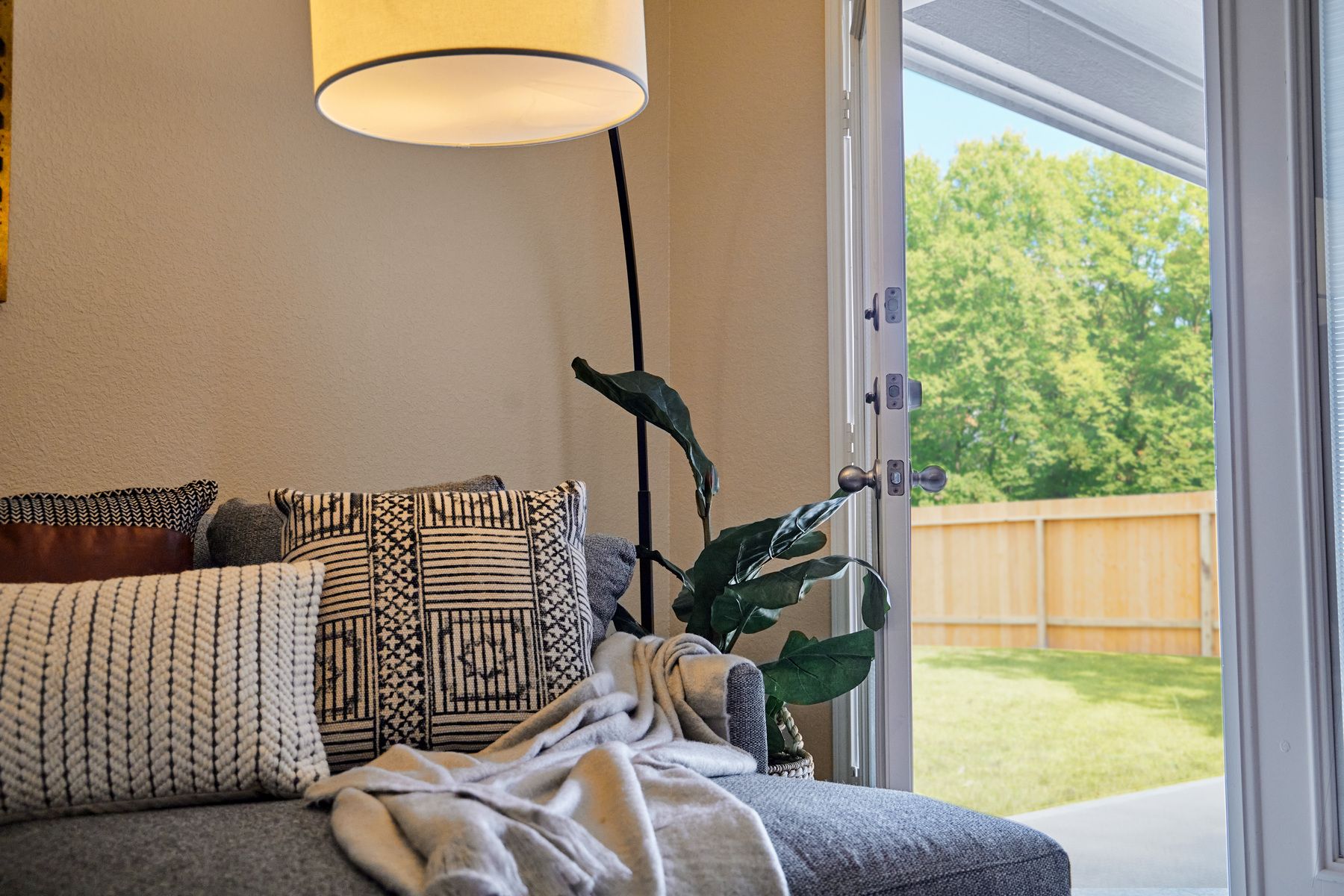 Staged living room with a gray couch and standing lamp.