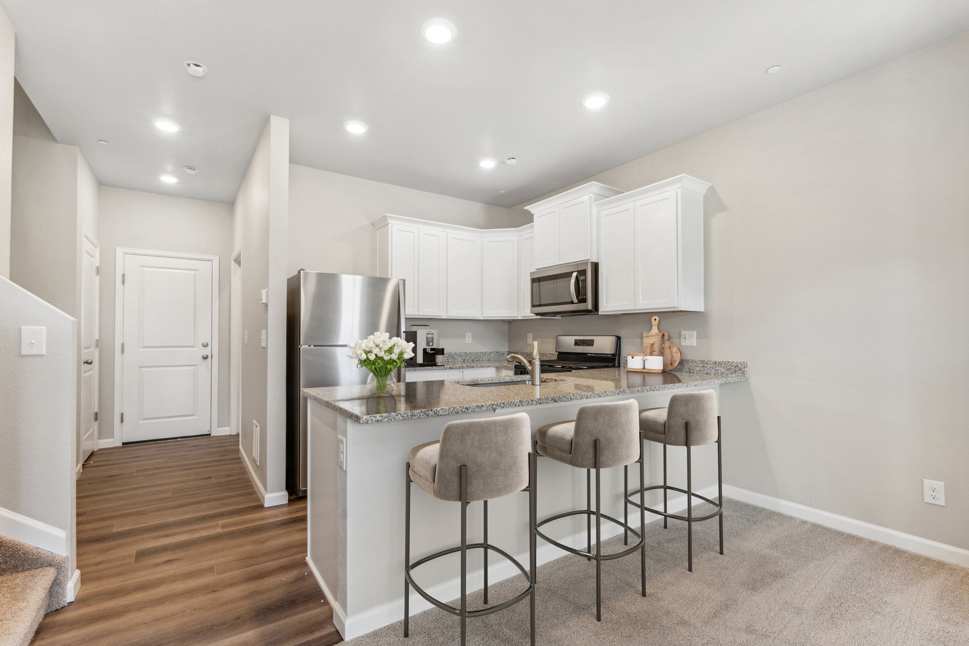 The kitchen has stainless steel appliances and plank flooring.