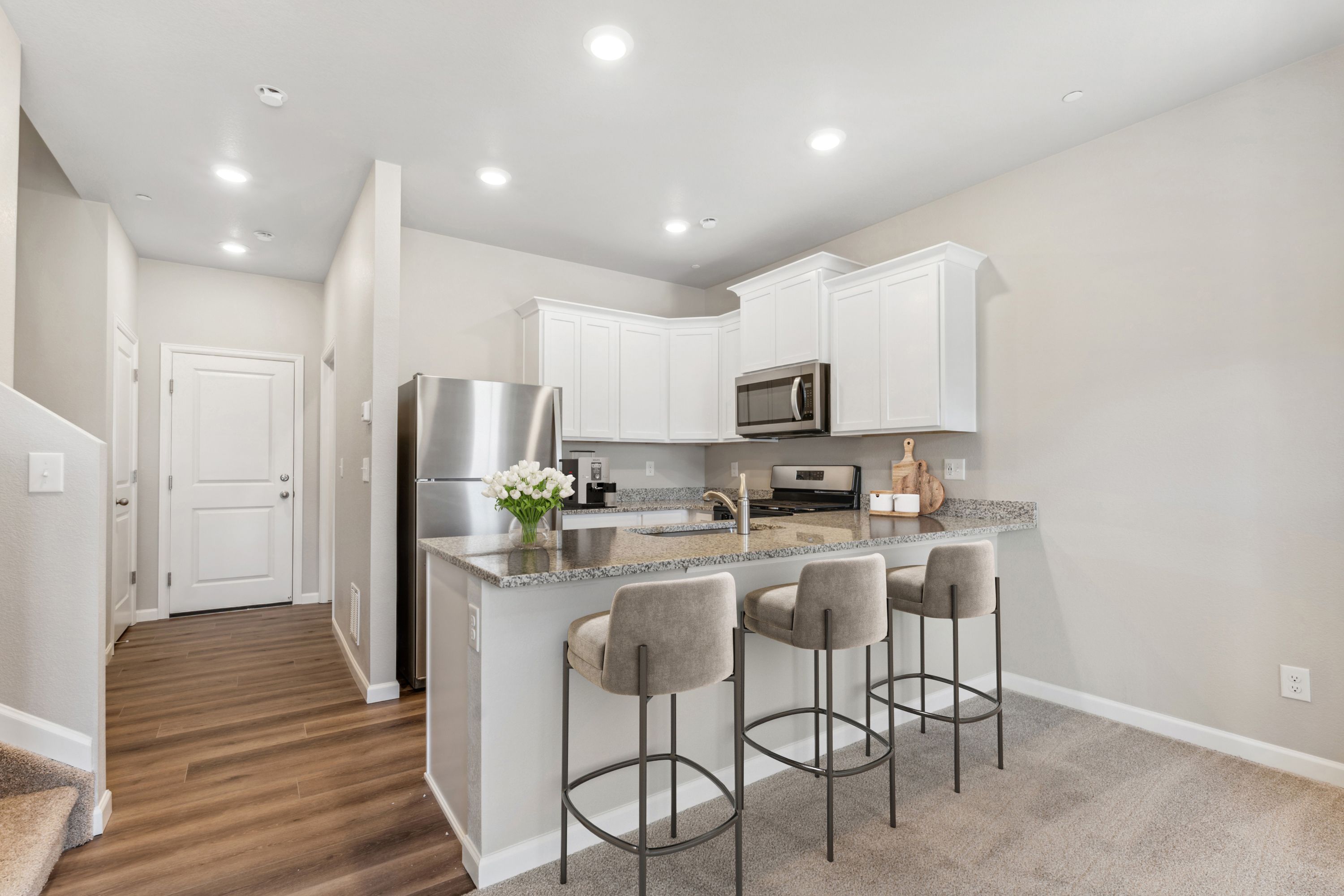The kitchen has stainless steel appliances and plank flooring.