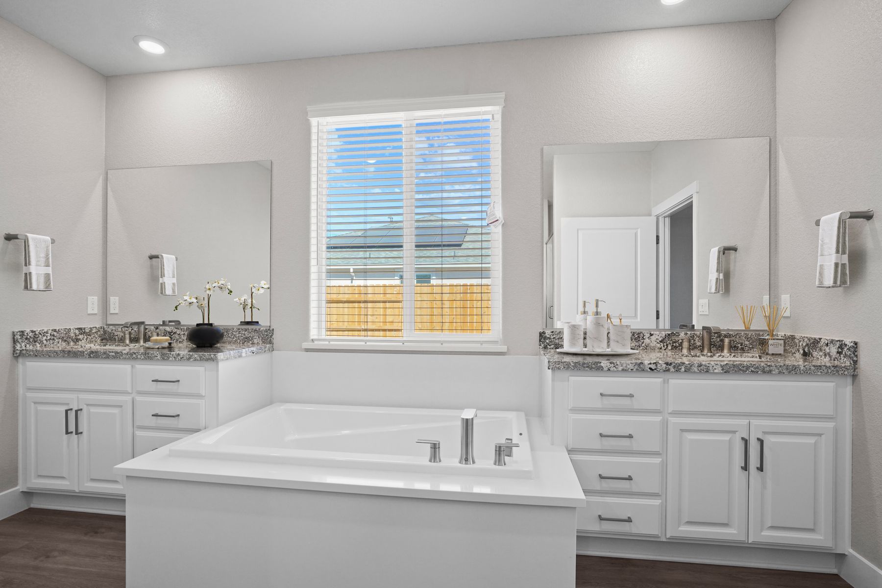 The master bathroom has a large vanity of either side of a soaking tub.