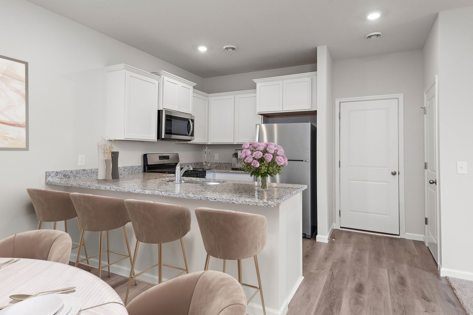 The kitchen has stainless steel appliances and plank flooring.