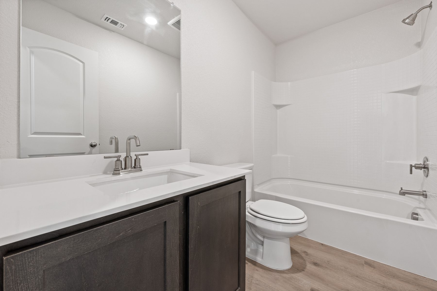 The secondary bathroom has a large vanity and shower tub combo.